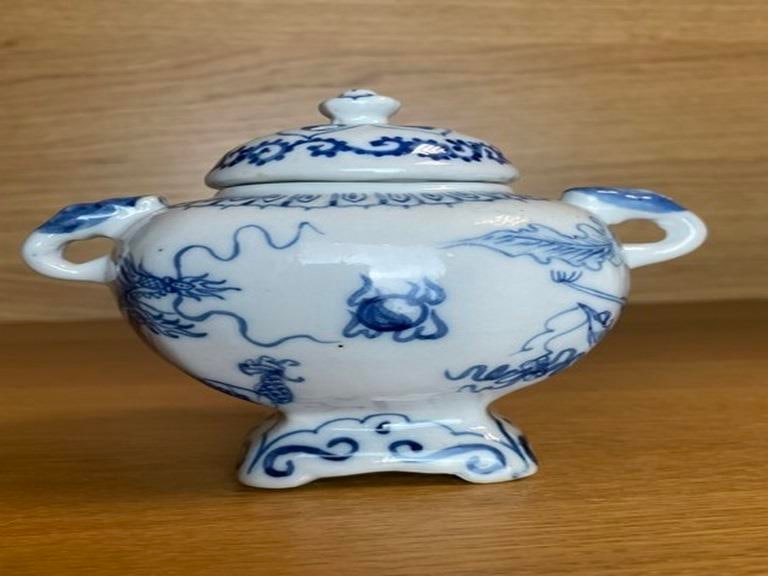 19TH CENTURY JAPANESE ANTIQUE PORCELAIN TEAPOT: This antique, blue and white Japanese porcelain teapot has a decorative knopped cap with a small breathing hole and dobin style handle connectors for interchanging rattan or bamboo handles that can be