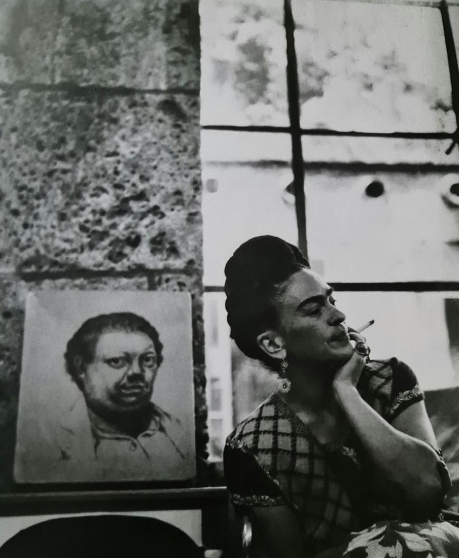 Frida Kahlo, Smoking Near Diego Rivera Painting, 1945: Subject: Smoking near Diego Rivera painting Subject/Title- Frida Kahlo Photos Type Of Print: Authentic Vintage Sheet Fed Photogravure/Heliogravure Date Of Print: 2021 Publisher: Taschen GmbH Paper: Me