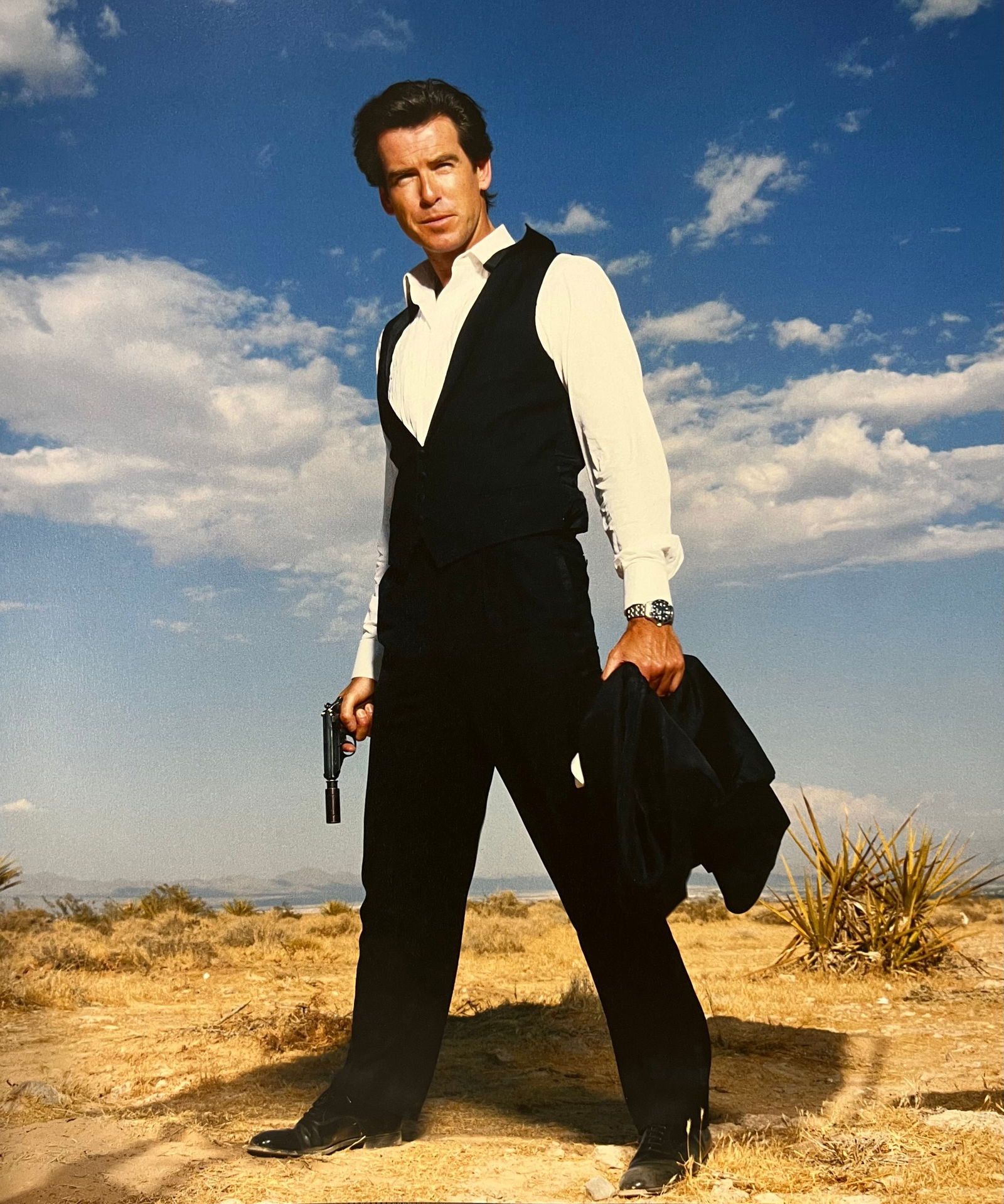Terry O'Neill, Pierce Brosnan Brought Bond Into Vogue With This Slick Three-Piece Brioni Suit, 1995: Photographer: Terry O’Neill CBE (30 July 1938 – 16 November 2019) was a British photographer, known for documenting the fashions, styles, and celebrities of the 1960s. Title: Pierce Brosnan Brough