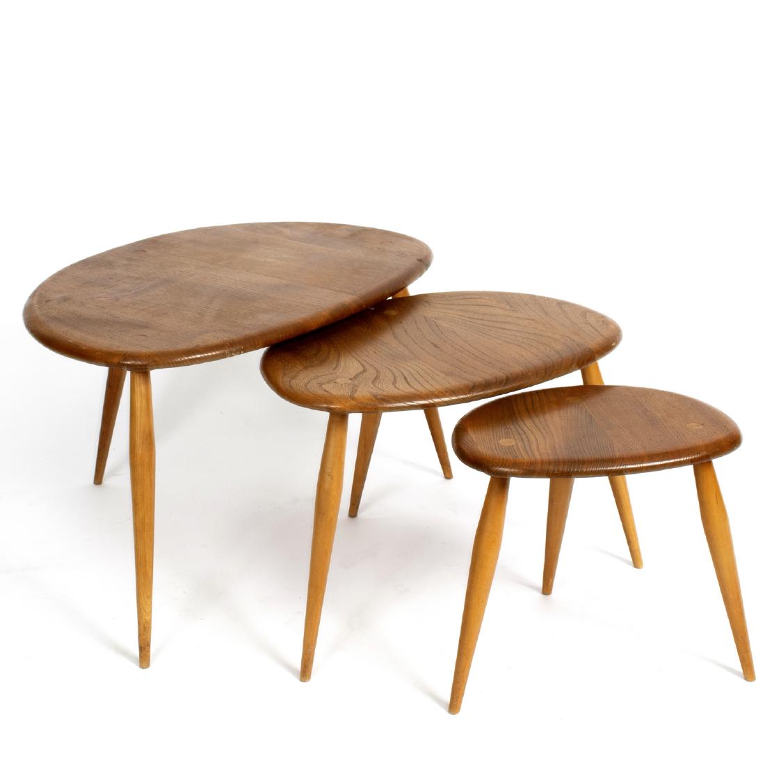 Ercol, a nest of three beech Pebble tables, on stylised: Ercol, a nest of three beech Pebble tables, on stylised triangular form on three turned tapering legs, the largest 66cm wide