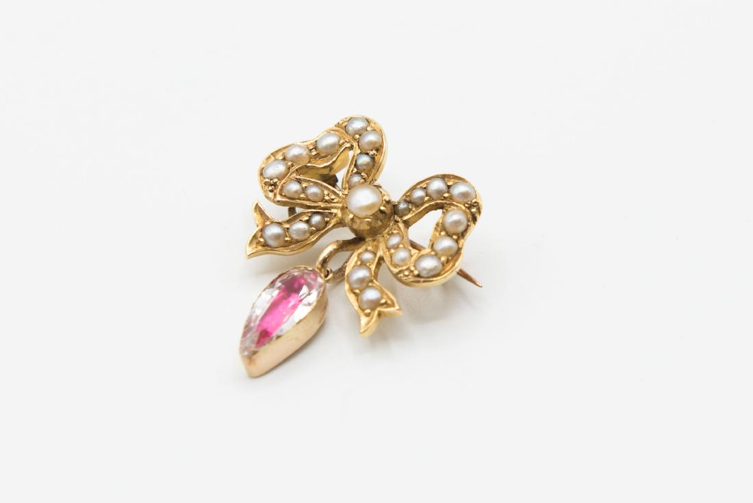 A LATE 19TH CENTURY SEED PEARL BROOCH, modelled as a: A LATE 19TH CENTURY SEED PEARL BROOCH, modelled as a bow set throughout with graduating seed pearl highlights, suspending an articulated oval cut foil backed clear stone. Stamped 18. Length 2cm. Width
