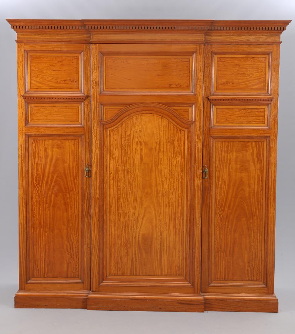 HOWARD & SONS A FINE LATE VICTORIAN SATINWOOD: HOWARD & SONS A FINE LATE VICTORIAN SATINWOOD BREAKFRONT WARDROBE, with dentil cornice above a centre door, labelled, with rectangular panel over an arch panel, flanked by a pair of three-panel doors,