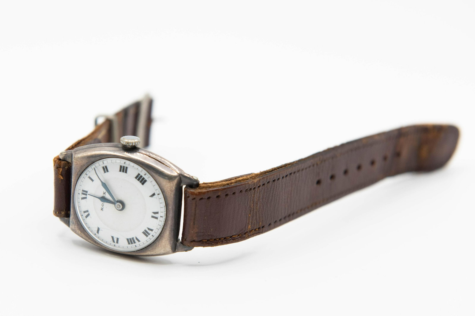 A SILVER ROLEX STRAP WATCH. Circular white enamel dial: A SILVER ROLEX STRAP WATCH. Circular white enamel dial with roman index and blued steel hands, cushion shaped case measuring 27.5 mm with snap on back internally signed Rolex 7 World's Records Geneve 