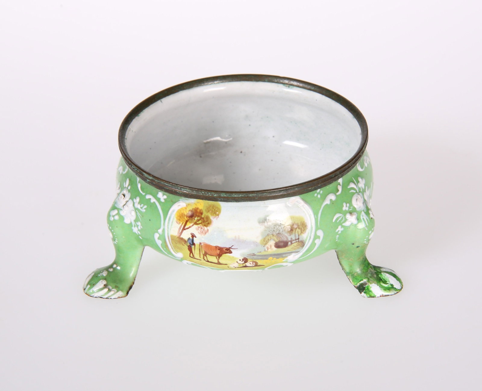 AN ENGLISH GREEN ENAMEL SALT CELLAR, decorated with: AN ENGLISH GREEN ENAMEL SALT CELLAR, decorated with three scroll bordered cartouches painted with rustic scenes of farmer and stock, 18th Century. Diameter 8cm