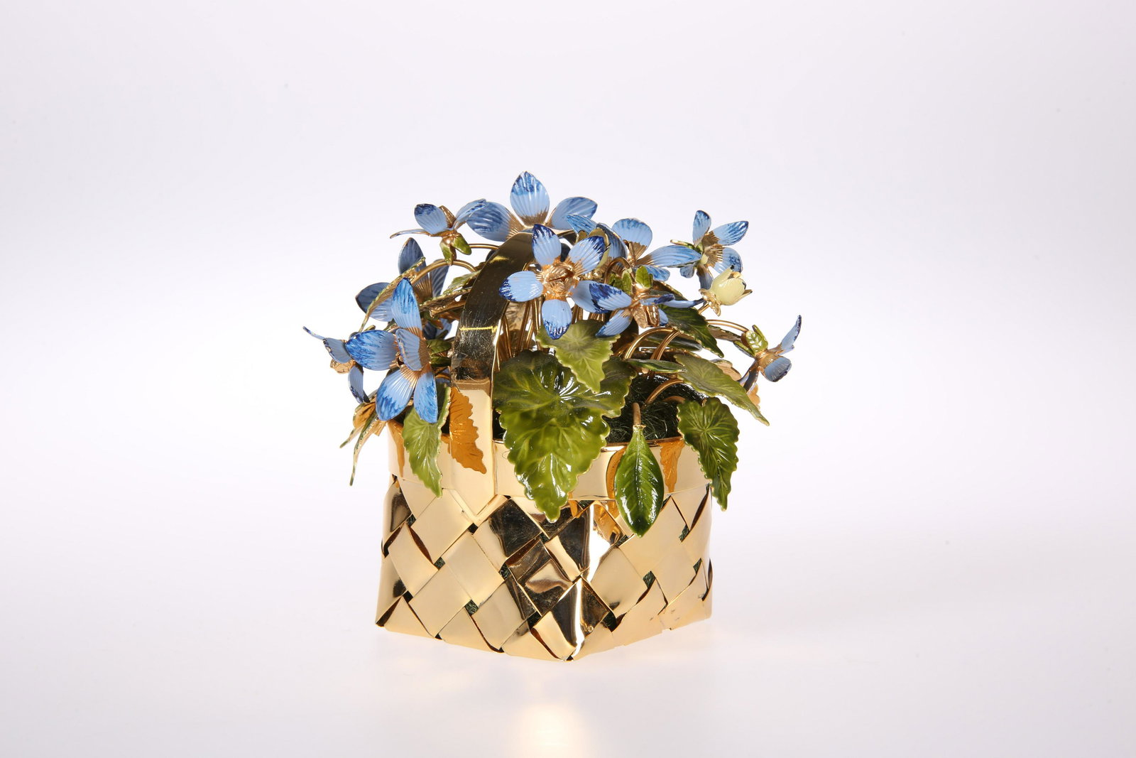 A STERLING SILVER-GILT AND ENAMEL BASKET OF FLOWERS, BY: A STERLING SILVER-GILT AND ENAMEL BASKET OF FLOWERS, BY CARTIER, the woven gilt basket, filled with stylised blue flowers and green leaves, signed. 9cm high