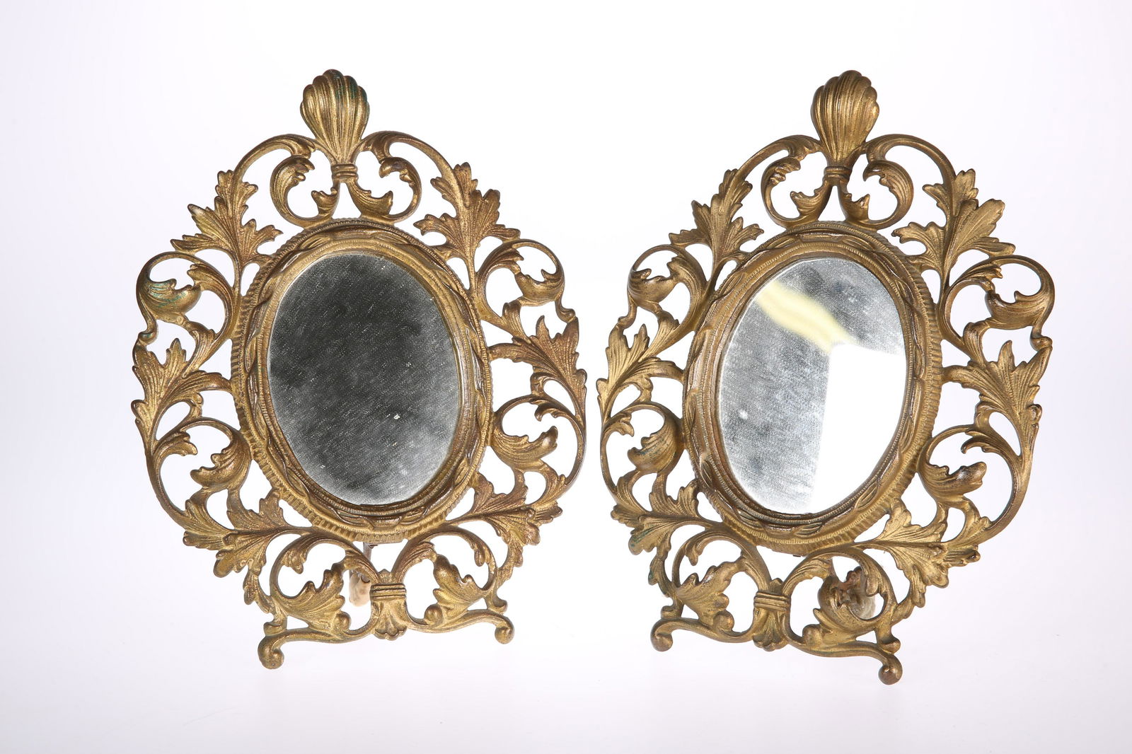 A PAIR OF 19TH CENTURY GILT-BRASS TABLE MIRRORS, each: A PAIR OF 19TH CENTURY GILT-BRASS TABLE MIRRORS, each openwork surround with scrolls and foliage, hinged easel back, oval mirror plates. 28.5cm