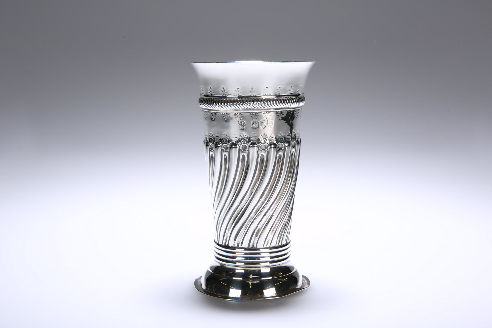 A VICTORIAN SILVER VASE, CHARLES STUART HARRIS, LONDON: A VICTORIAN SILVER VASE, CHARLES STUART HARRIS, LONDON 1893, of tapering cylindrical form, half gadrooned, on a domed circular foot, engraved with a crest. 12.5cm, 3.9 troy ounces