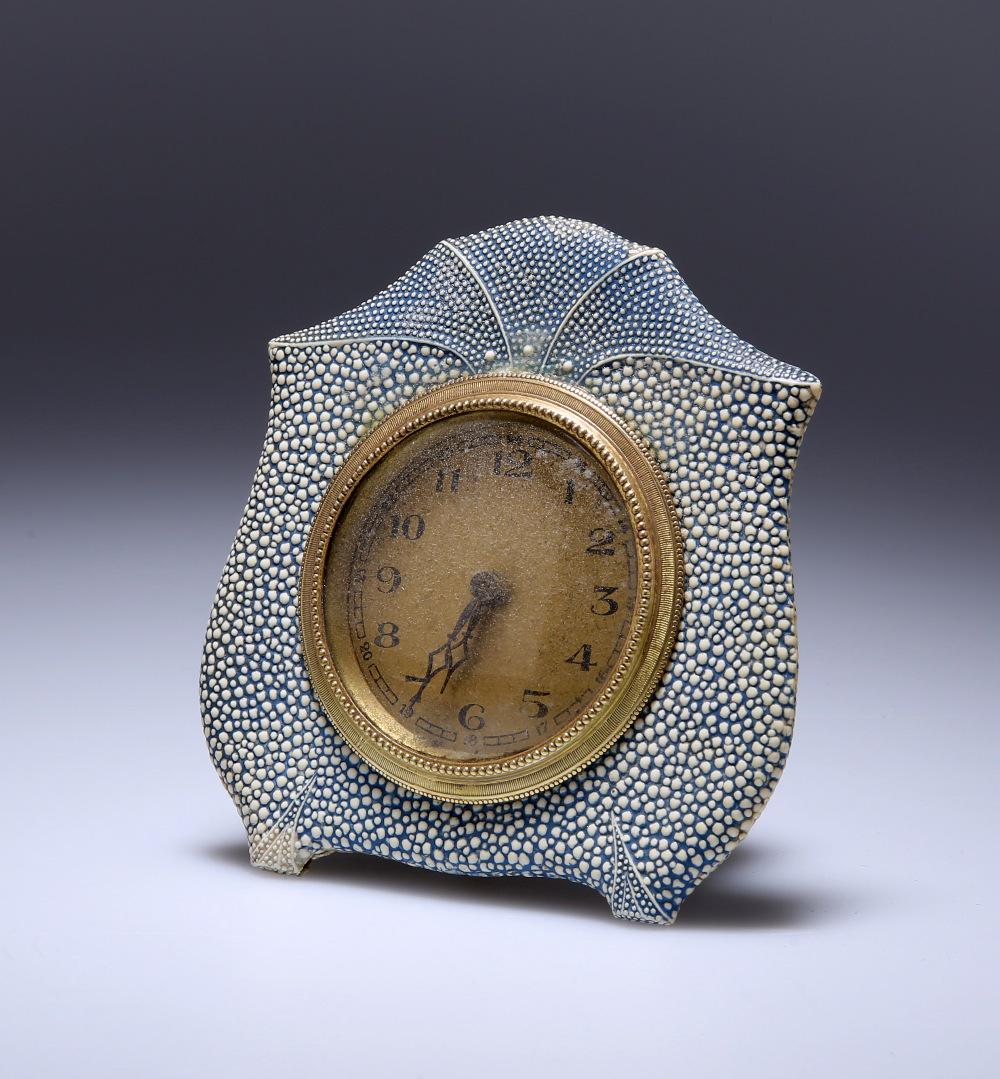A BLUE SHAGREEN DESK CLOCK, c. 1920, the circular gilt: A BLUE SHAGREEN DESK CLOCK, c. 1920, the circular gilt dial with Arabic numerals within a shaped circular case with arched crest. Overall 10.5cm by 10cm