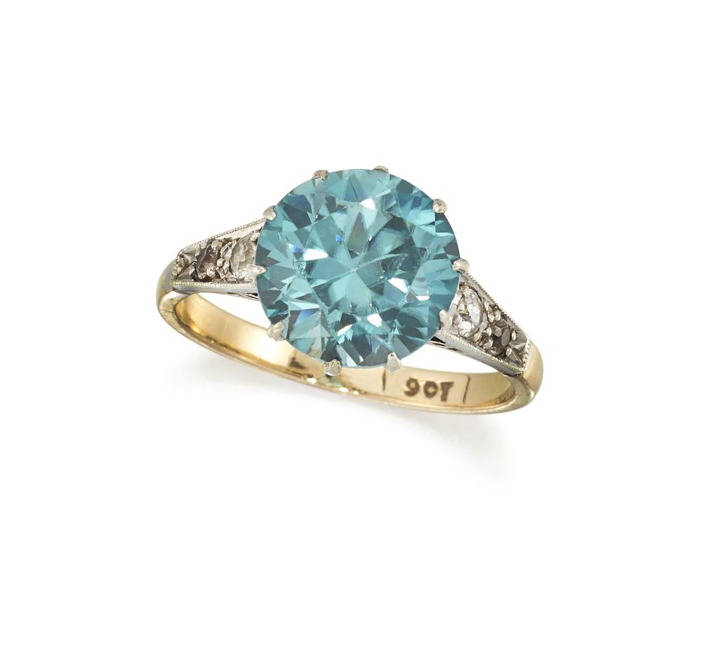 A ZIRCON AND DIAMOND RINGÂ The claw-set circular-cut: A ZIRCON AND DIAMOND RINGÂ The claw-set circular-cut blue zircon, between millegrain-edged shoulders accented by brilliant-cut diamonds, to a tapering hoop, stamped 9CT, ring size M.Â Gross weig