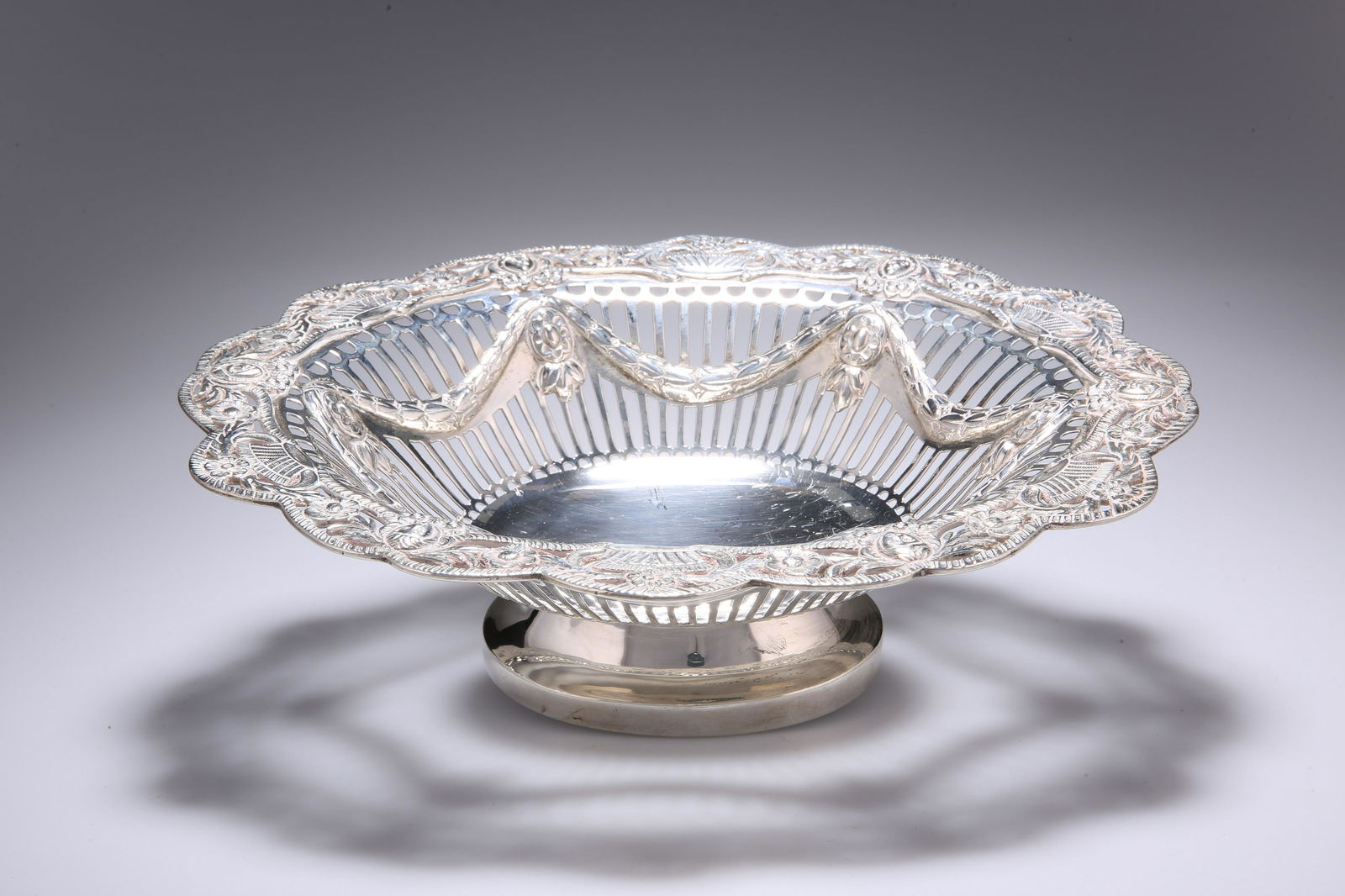 AN EDWARDIAN SILVER DISH,Â byÂ Charles Stuart Harris,: AN EDWARDIAN SILVER DISH,Â byÂ Charles Stuart Harris, London 1901, oval with pierced sides, chased with floral swags, the rim with masks and baskets of flowers. 8.5cm high, 26.5cm long, 22.7cm wid