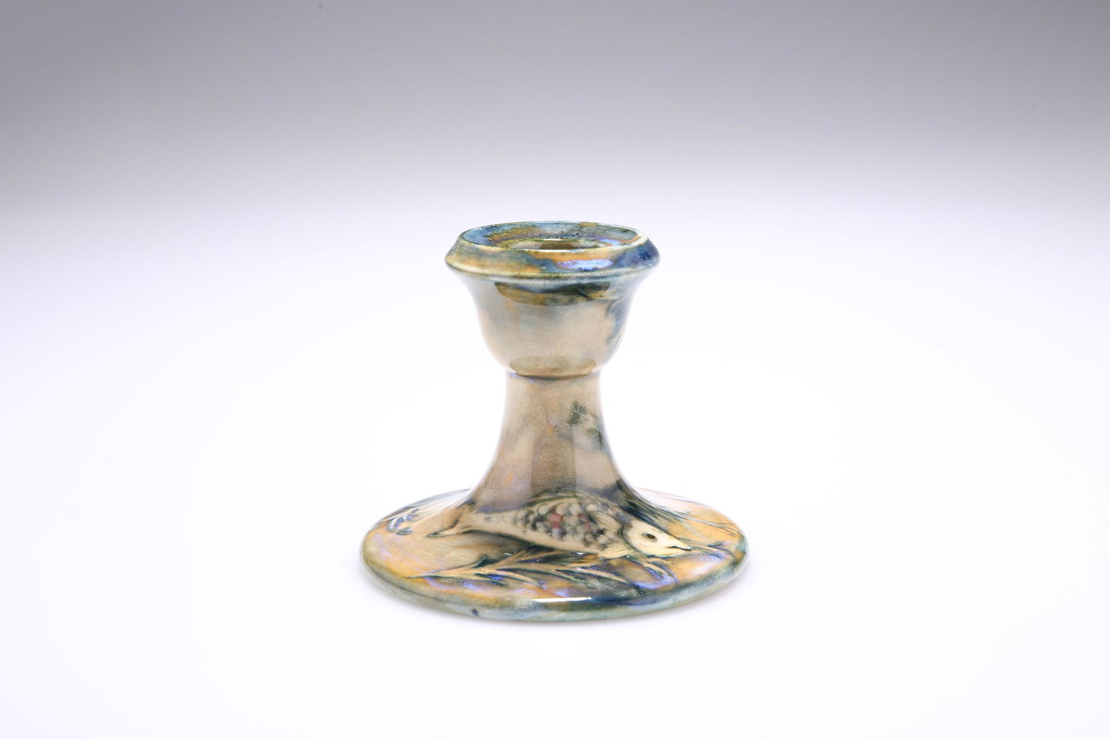 WILLIAM MOORCROFT (1872-1945) A MOORCROFT POTTERY: WILLIAM MOORCROFT (1872-1945) A MOORCROFT POTTERY "FISH" CANDLESTICK, 1920'S/30'S, tubelined and hand-painted with two fish, slate blue initials, impressed marks. 8cm high