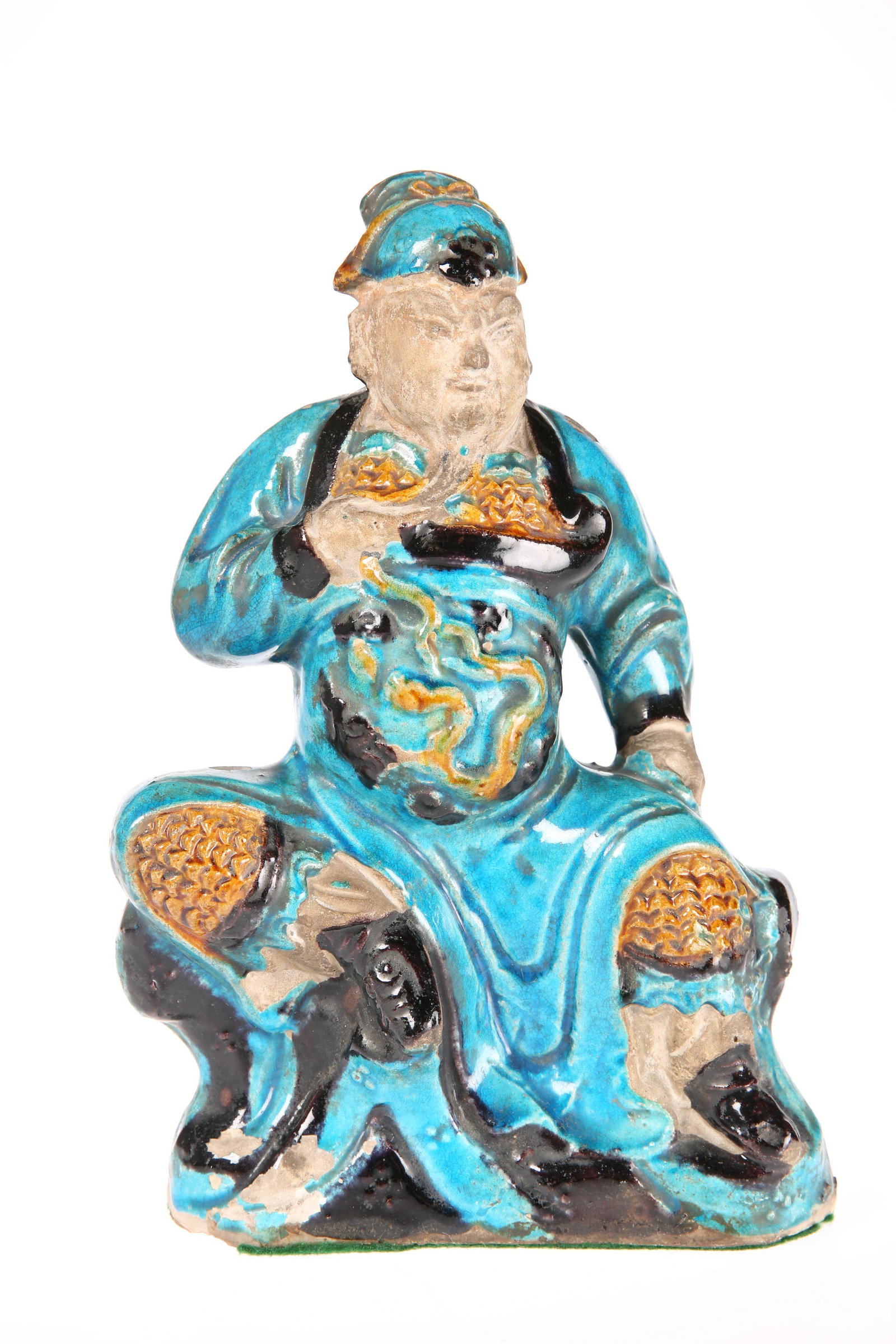 A CHINESE SANCAI GLAZED FIGURE OF A GUARDIAN, LATE MING: A CHINESE SANCAI GLAZED FIGURE OF A GUARDIAN, LATE MING DYNASTY, modelled seated with one knee raised, decorated in turquoise, blue and amber glazes. 28cm high