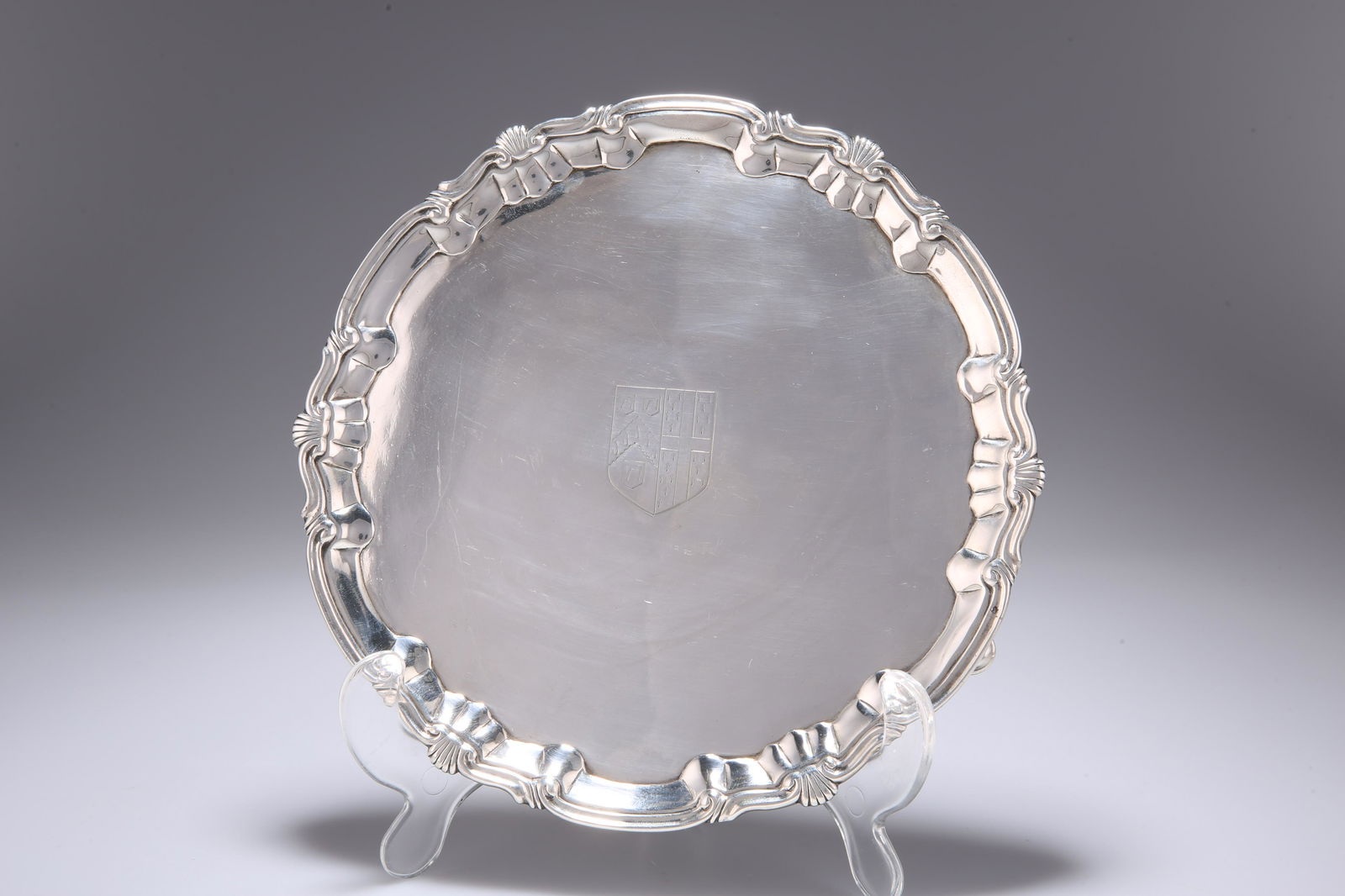 A GEORGE II SILVER SALVER, by William & Robert Peaston,: A GEORGE II SILVER SALVER, by William & Robert Peaston, London 1757, circular with shell and scroll edge, engraved with an armorial, raised on three hoof feet. 20.5cm diameter, 12.2 troy ounces