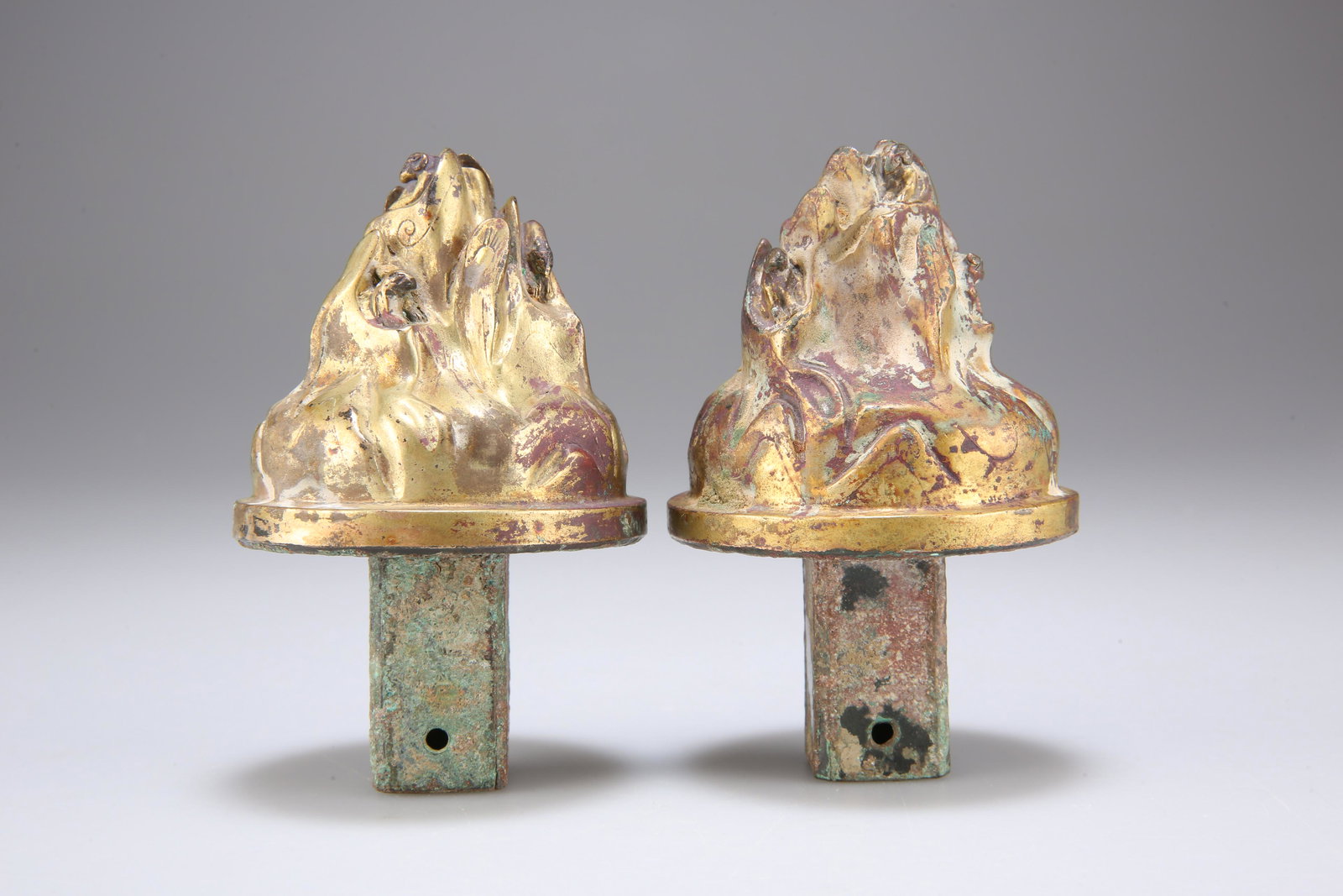 A PAIR OF GILT CHARIOT FITTINGS, HAN DYNASTY, the: A PAIR OF GILT CHARIOT FITTINGS, HAN DYNASTY, the chariot fittings would have embellished one end of the yoke, in the shape of a celestial mountain, the reverse with square socket. 9cm high
