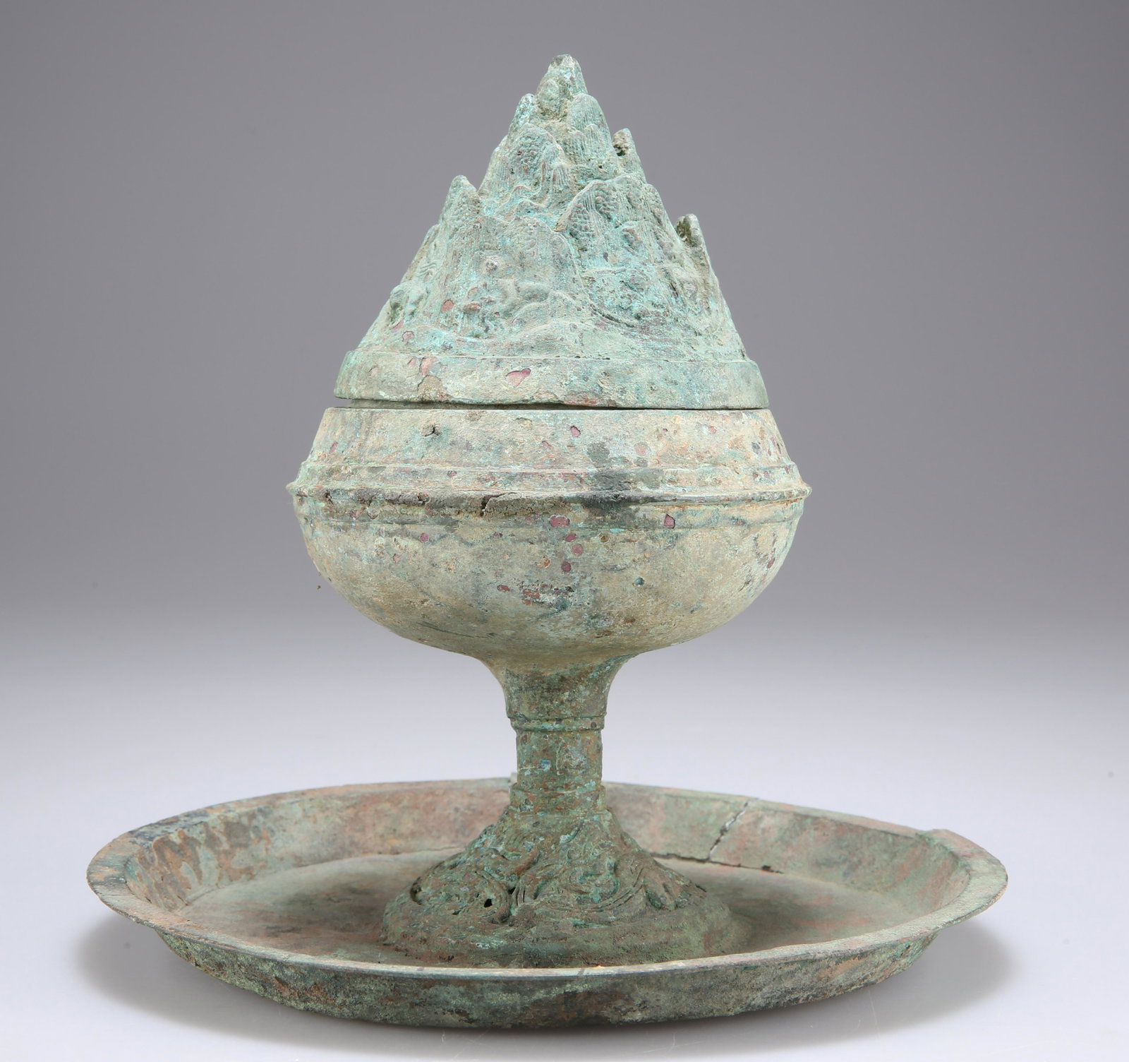 A BRONZE 'HILL' CENSER AND COVER, BOSHANLU, SHANLU HAN: A BRONZE 'HILL' CENSER AND COVER, BOSHANLU, SHANLU HAN DYNASTY (206 BC-AD 220), raised on a stem foot with openwork coiled dragon motif, upon a circular drip plate, the conical cover cast in openwork 