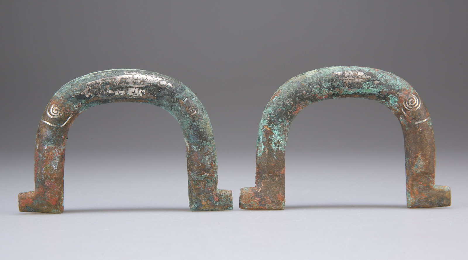 A PAIR OF SILVER INLAID YOKE FITTINGS, LATE WARRING: A PAIR OF SILVER INLAID YOKE FITTINGS, LATE WARRING STATES OR EARLY HAN DYNASTY, the rein brackets decorated with some geometrical patterns. 8cm wide