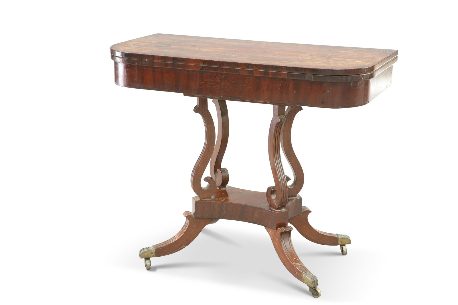 A REGENCY MAHOGANY FOLDOVER CARD TABLE, the rounded: A REGENCY MAHOGANY FOLDOVER CARD TABLE, the rounded rectangular top with rosewood banding, raised on four reeded S-scroll supports issuing from a platform base with reeded downswept legs, terminating