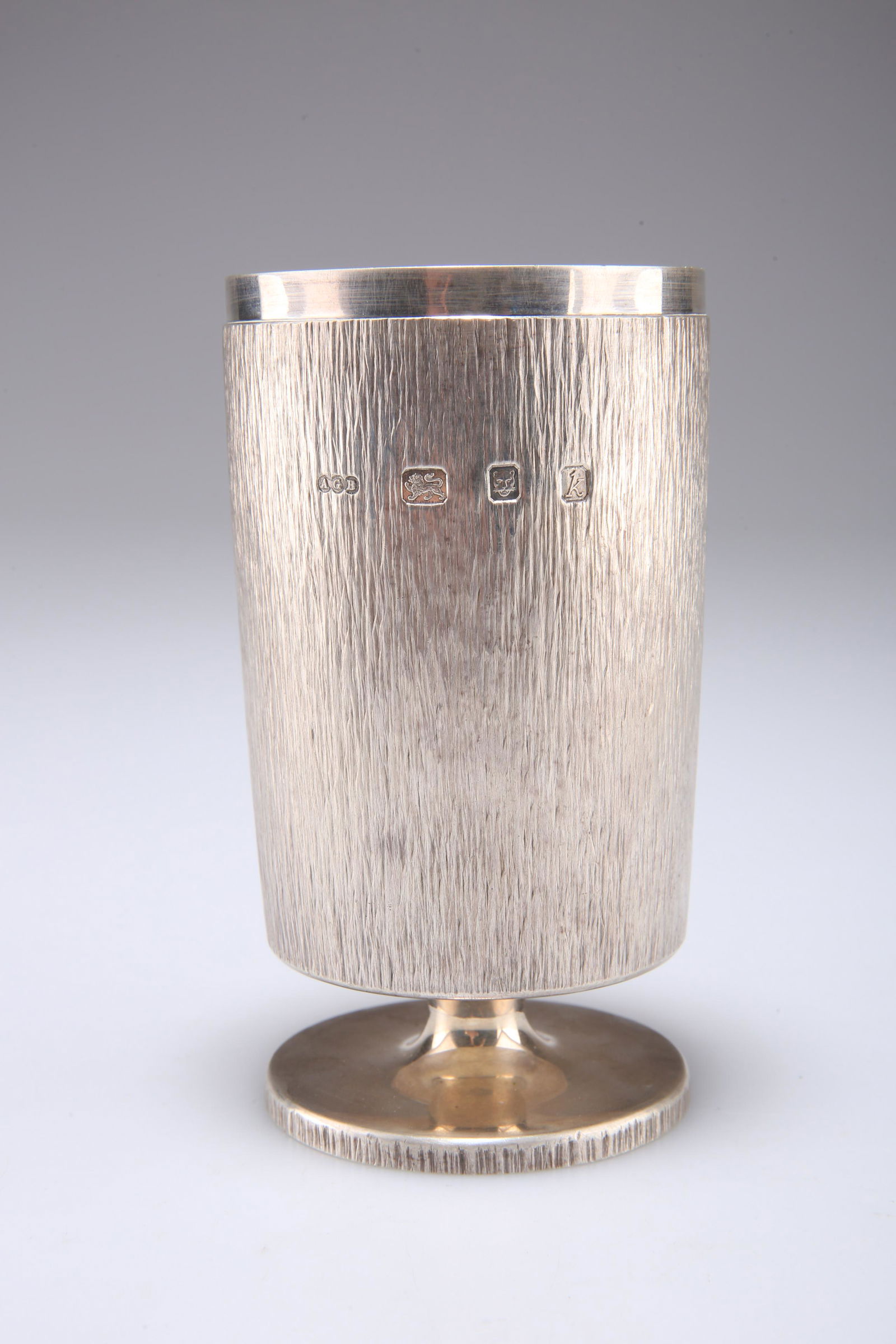 AN ELIZABETH II SILVER GOBLET, by Gerald Benney, London: AN ELIZABETH II SILVER GOBLET, by Gerald Benney, London 1965, the cylindrical cup with textured bark effect ground, raised on a short waisted stem issuing from a stepped circular foot with bark effect