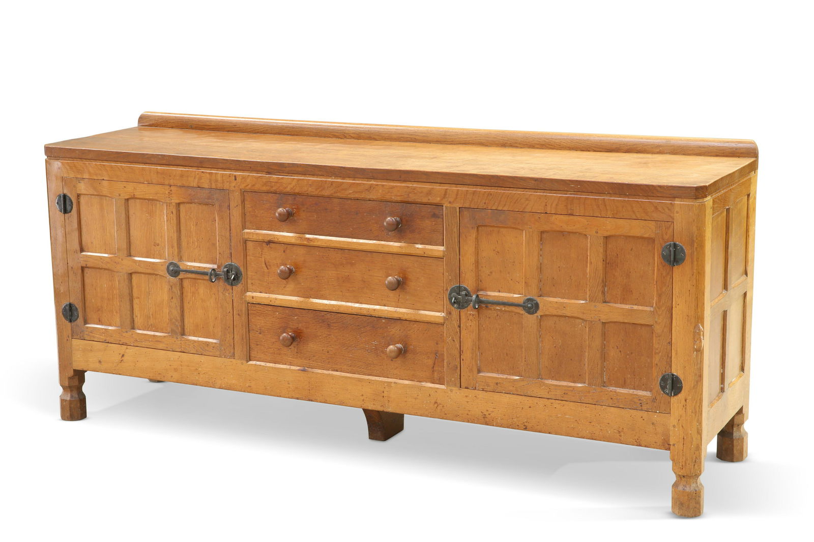 ROBERT THOMPSON OF KILBURN, A MOUSEMAN OAK SIDEBOARD,: ROBERT THOMPSON OF KILBURN, A MOUSEMAN OAK SIDEBOARD, the rectangular top above a pair of six-panel doors, fitted with wrought iron latches and hinges, flanking three graduated drawers with turned pul