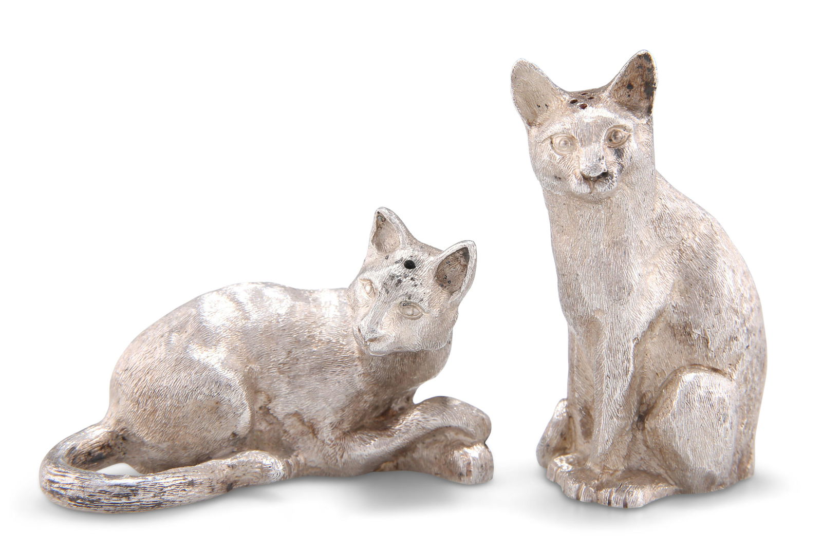 A PAIR OF ELIZABETH II SILVER NOVELTY SALT AND PEPPER POTS,: A PAIR OF ELIZABETH II SILVER NOVELTY SALT AND PEPPER POTS, by Richard Comyns, London 1990, in the form of cats, the pepper cast seated on its haunches, the salt lying down. (2) Tallest 6.5cm high, 8.