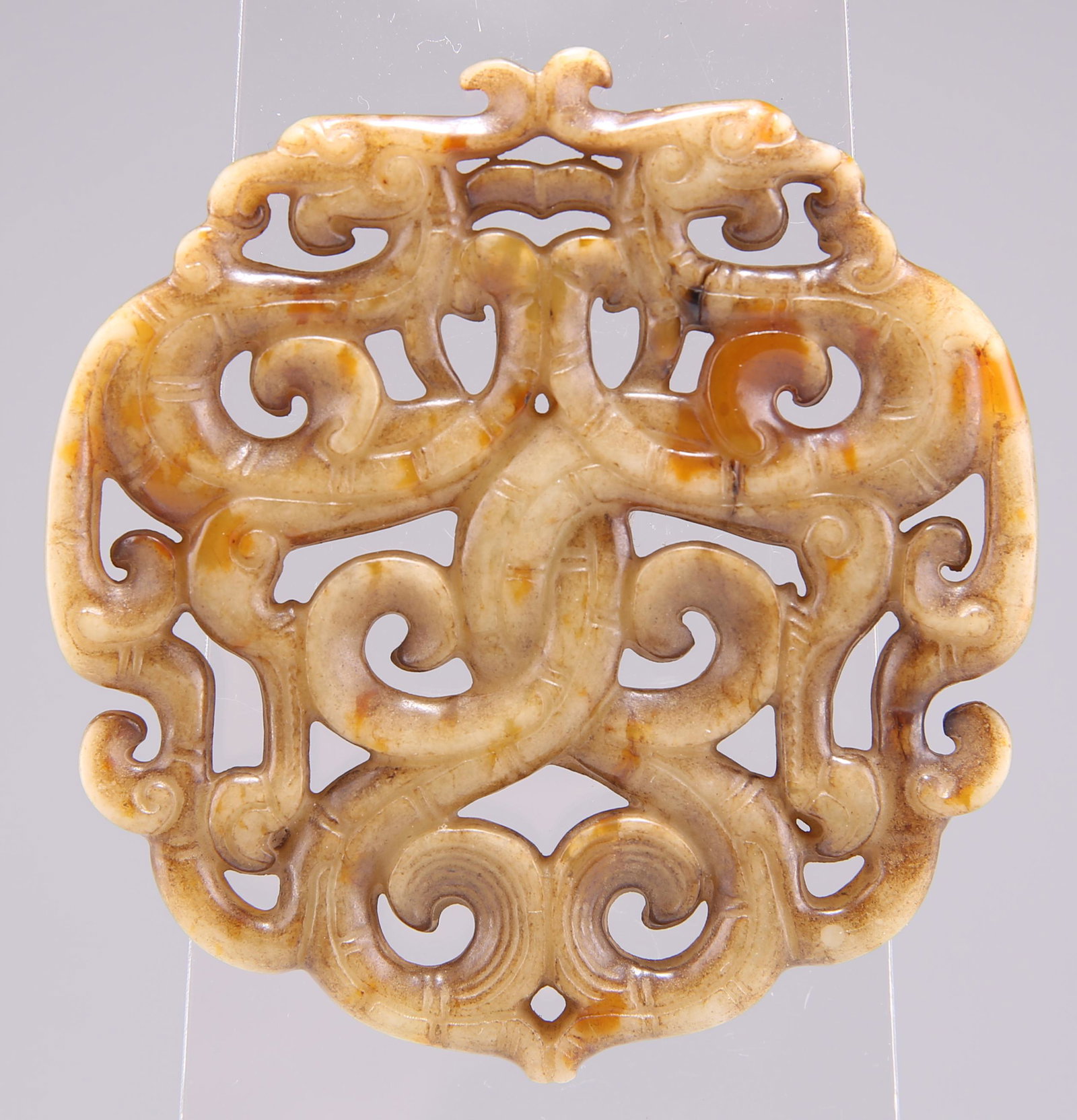 A CHINESE JADE 'PHOENIX' PENDANT, POSSIBLY 18TH CENTURY, of scrolling openwork design. 6.5cm diamete (1 of 2)