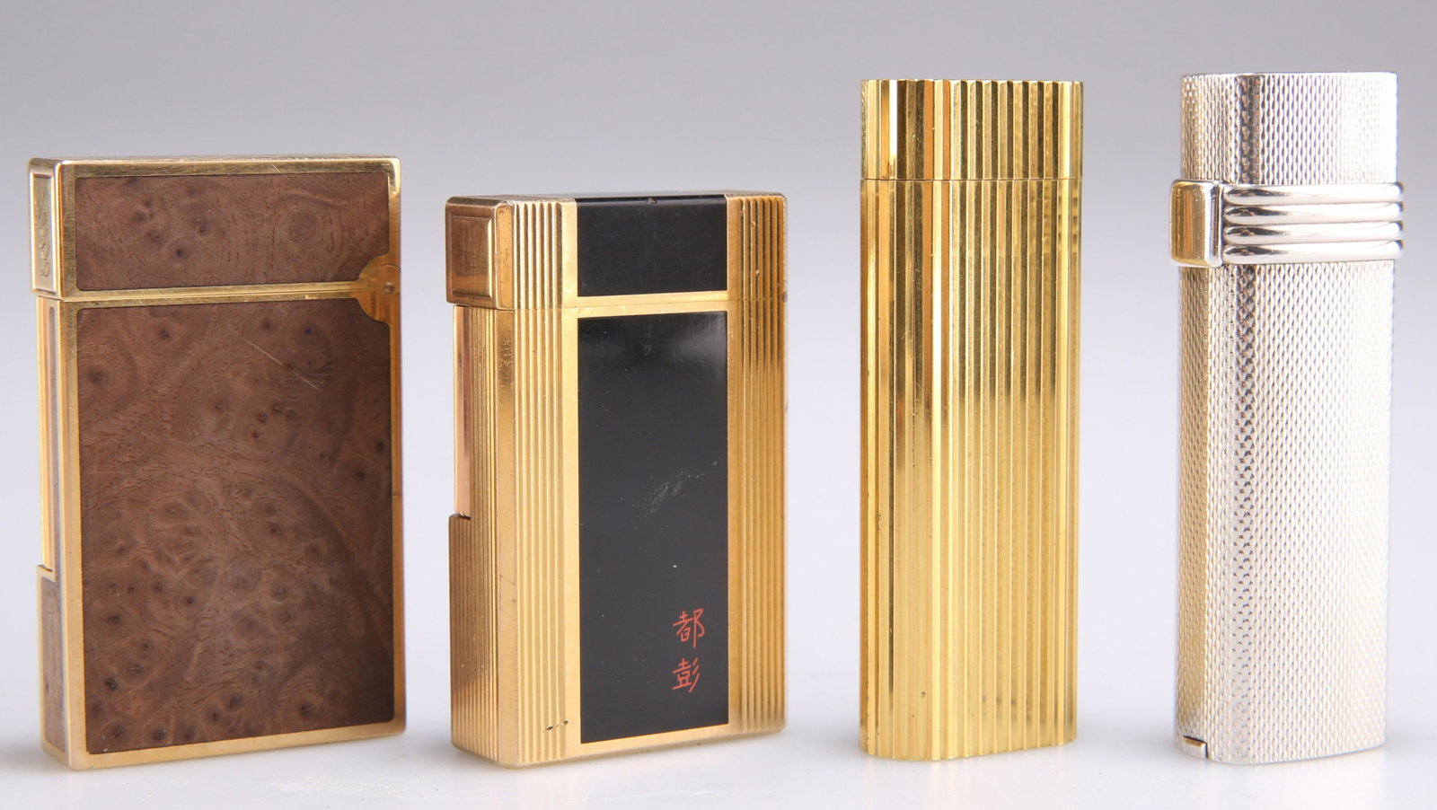 A GROUP OF FOUR LIGHTERS: A GROUP OF FOUR LIGHTERS, comprising Cartier, Christian Dior and two Dupont. (4) Cartier 7cm high
