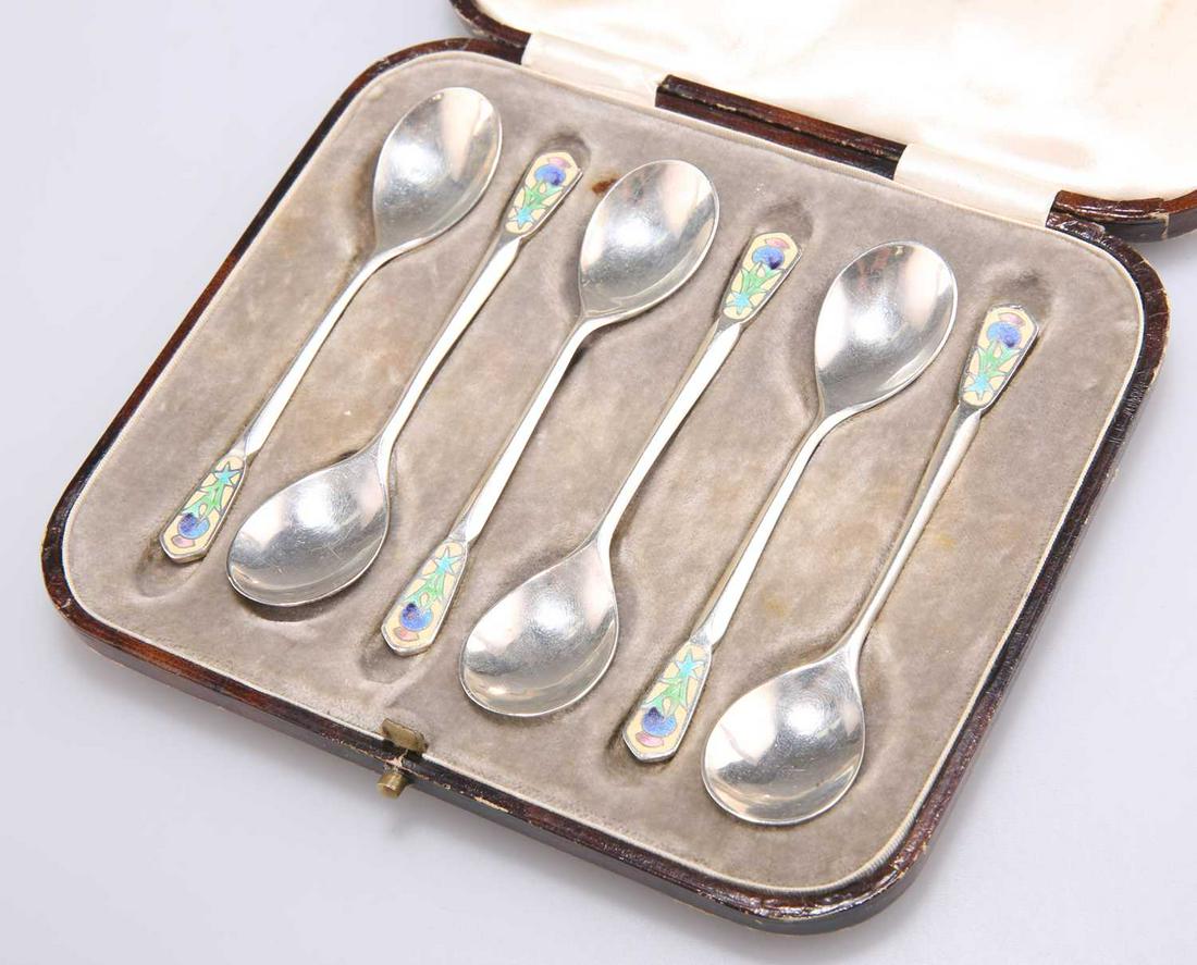 A SET OF SIX ART DECO SILVER AND ENAMEL COFFEE SPOONS: A SET OF SIX ART DECO SILVER AND ENAMEL COFFEE SPOONS, by Bernard Instone, Birmingham 1930, each terminal enamelled with a thistle, cased. 9.6cm long, 1.8 troy ounces Qty: 6