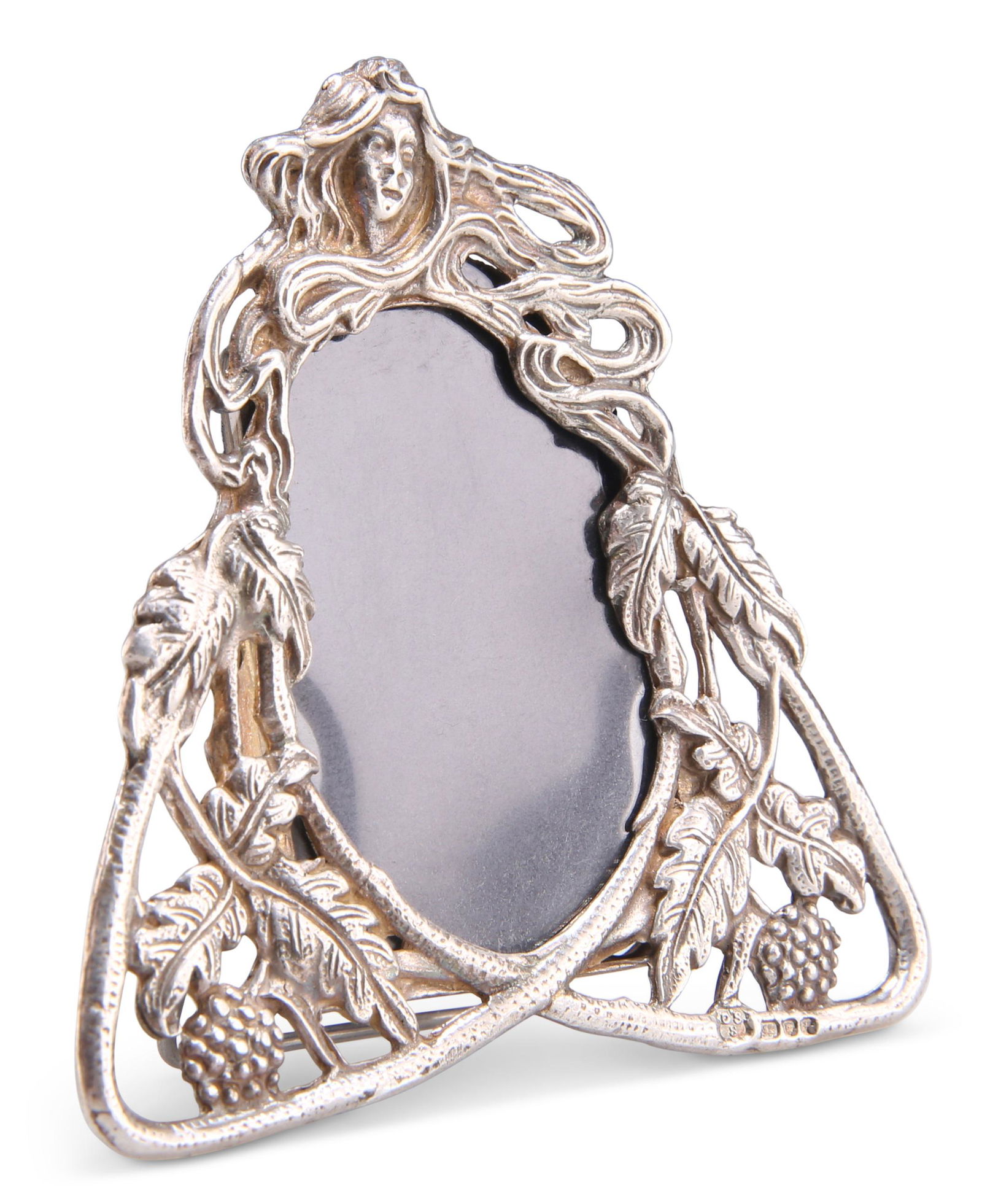 AN ELIZABETH II SILVER MINIATURE PHOTOGRAPH FRAME: AN ELIZABETH II SILVER MINIATURE PHOTOGRAPH FRAME by David Shaw Silverware Ltd, London 1982, Art Nouveau style, the triquetra pierced frame with leaves and berries, surmounted by a female head with fl