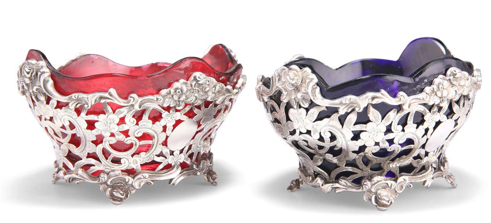 A PAIR OF VICTORIAN SILVER BASKETS: A PAIR OF VICTORIAN SILVER BASKETS by Charles Stuart Harris, London 1897, of shaped oval form, pierced and chased with C-scrolls, acanthus and flowers, raised on splayed floriform feet, one with a rub