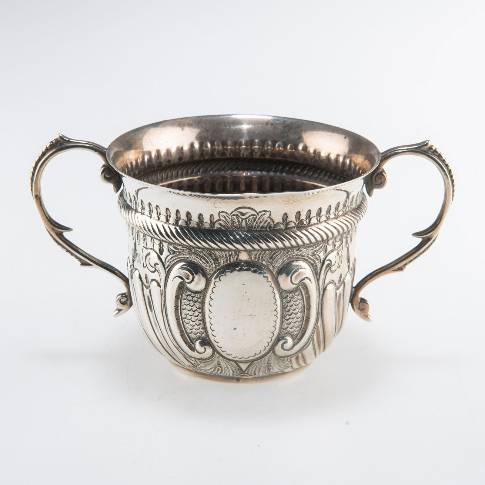 A GEORGIAN STYLE SILVER PORRINGER: A GEORGIAN STYLE SILVER PORRINGER by Charles Stuart Harris, London 1898, chased with scrolls and with beaded scroll handles. 14cm wide across handles, 5 troy ounces
