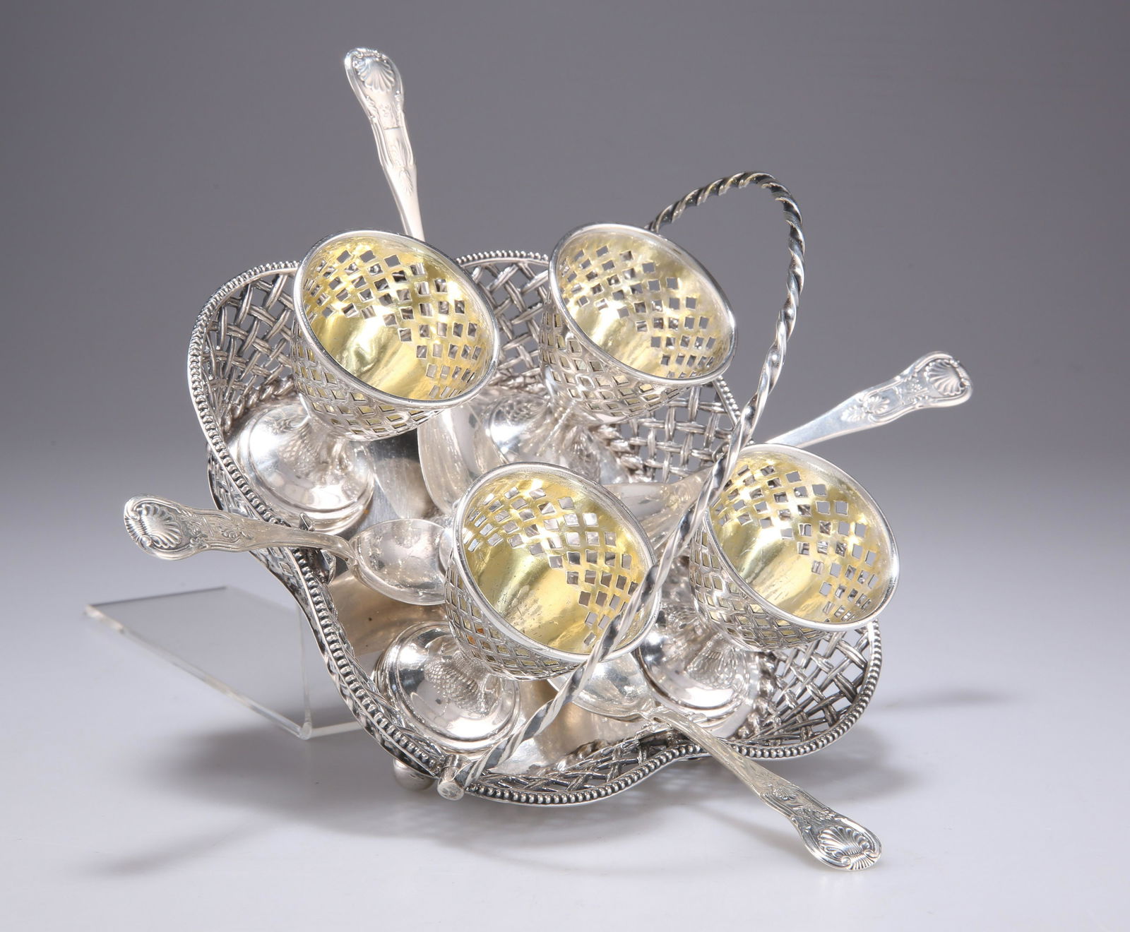 A VICTORIAN SILVER EGG CRUET: A VICTORIAN SILVER EGG CRUET by Henry Wilkinson & Co, Sheffield 1859, the lobed stand with latticework sides and swing-handle, raised on bun feet, crested, with four pierced egg cups and four asso