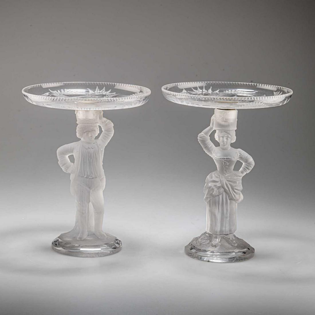 A PAIR OF FIGURAL TAZZAS, BY JOHN FORD & CO, HOLYROOD GLASSWORKS, EDINBURGH, CIRCA 1870: A PAIR OF FIGURAL TAZZAS, BY JOHN FORD & CO, HOLYROOD GLASSWORKS, EDINBURGH, CIRCA 1870 modelled as a gentleman and his female companion in frosted glass, each standing with one hand upon their hi
