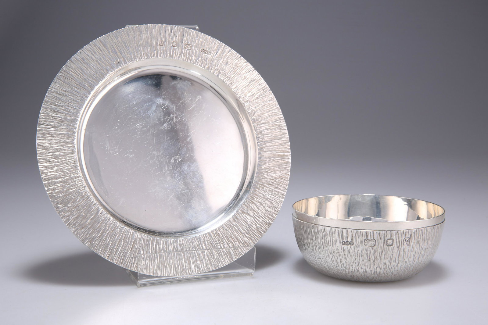 GERALD BENNEY: AN ELIZABETH II SILVER BOWL AND PLATE: GERALD BENNEY: AN ELIZABETH II SILVER BOWL AND PLATE by Gerald Benney, London 1968, circular, each with bark effect textured ground. (2) Plate 15.5cm diameter, 9 troy ounces gross Gerald Benney was o