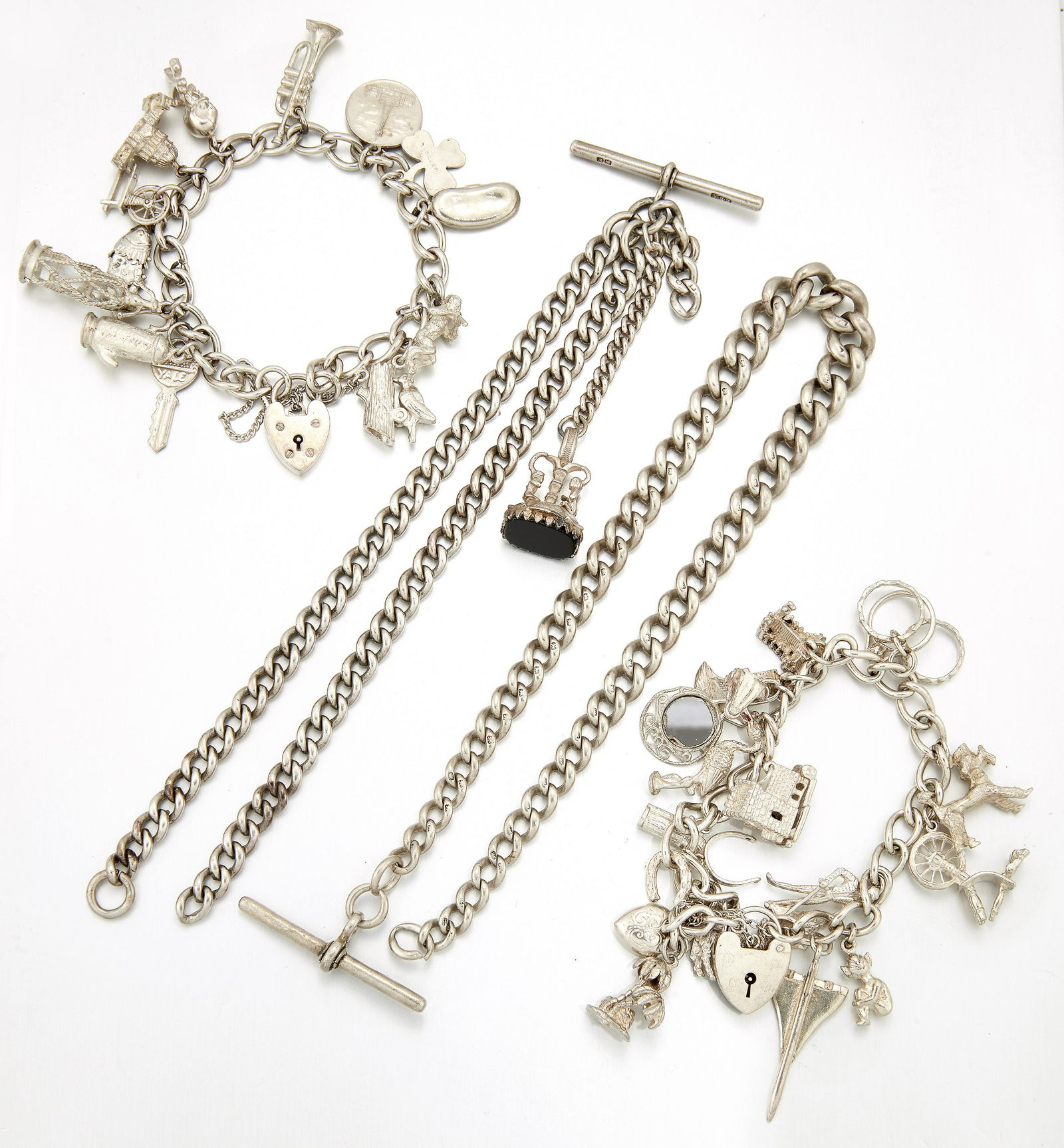 TWO SILVER CHARM BRACELETS AND TWO SILVER ALBERT CHAINS: TWO SILVER CHARM BRACELETS AND TWO SILVER ALBERT CHAINS one Albert complete with a fob seal. (4) 6 troy ounces gross
