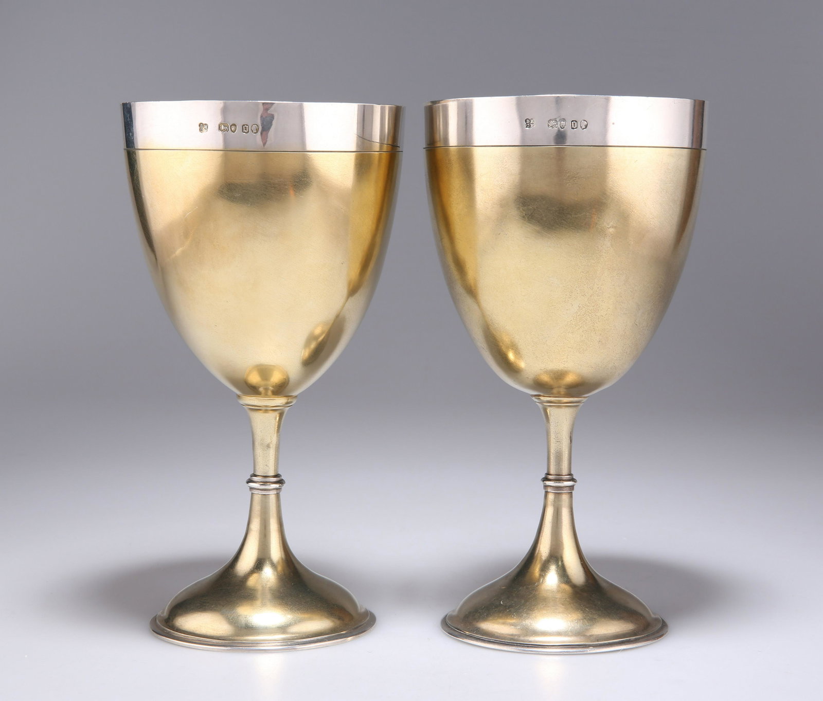 A LARGE PAIR OF VICTORIAN SILVER-GILT GOBLETS: A LARGE PAIR OF VICTORIAN SILVER-GILT GOBLETS by Daniel & Charles Houle, London 1869, the ovoid bowls with silver collar, raised on a knopped slender steam continuing to a domed circular foot. (2)