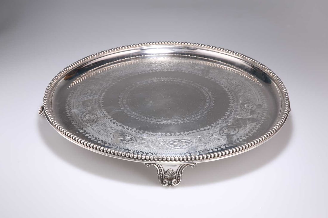 A MASSIVE VICTORIAN SILVER SALVER: A MASSIVE VICTORIAN SILVER SALVER by Frederick Elkington, Birmingham 1871, circular, with a border of large beads, the base engraved with decoration, raised on four leaf and scroll form feet, engraved