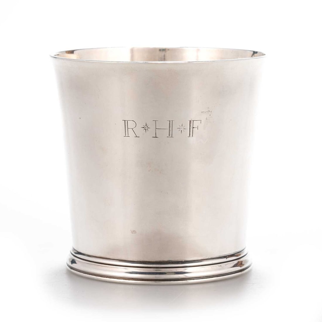 A QUEEN ANNE SILVER BEAKER: A QUEEN ANNE SILVER BEAKER by John East, London 1704, of tapering cylindrical form with moulded foot rim, engraved R*H*F, paper label of John Taylor. 8.3cm high, 5.3 troy ounces The marks are clear.