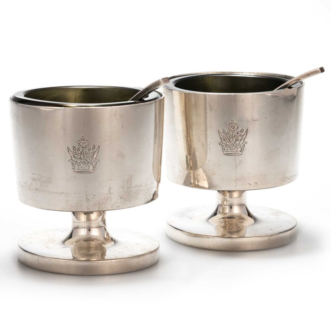 GERALD BENNEY: A PAIR OF SILVER SALTS: GERALD BENNEY: A PAIR OF SILVER SALTS by Gerald Benney, London 1965, of cylindrical-form, raised on a stepped circular foot, with green glass liners and original spoons. (4) 8.5cm high, 14 troy ounces