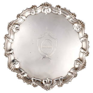 A GEORGE II SILVER SALVER: A GEORGE II SILVER SALVER by William Grundy, London 1754, of shaped circular-form, raised on three leaf-capped scroll feet, with shell and scroll border, engraved with a coat of arms. 38.5cm diameter,