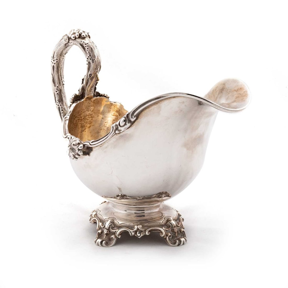 A VICTORIAN SILVER SAUCEBOAT: A VICTORIAN SILVER SAUCEBOAT by Stephen Smith & William Nicholson, London 1852, grapevine pattern, the substantial bowl raised on a scroll-cast base with four conforming feet. 20cm long, 14.9 troy