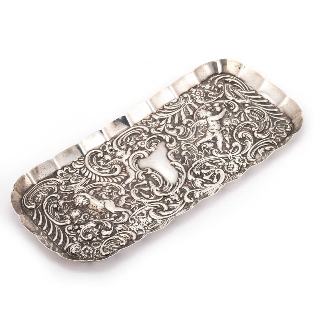 A VICTORIAN SILVER DISH: A VICTORIAN SILVER DISH by William Comyns & Sons Ltd (Richard Comyns), London 1899, of shaped rectangular form, repoussé with Putti, flowerheads and C-scrolls. 23.7cm wide, 4.1 troy ounces