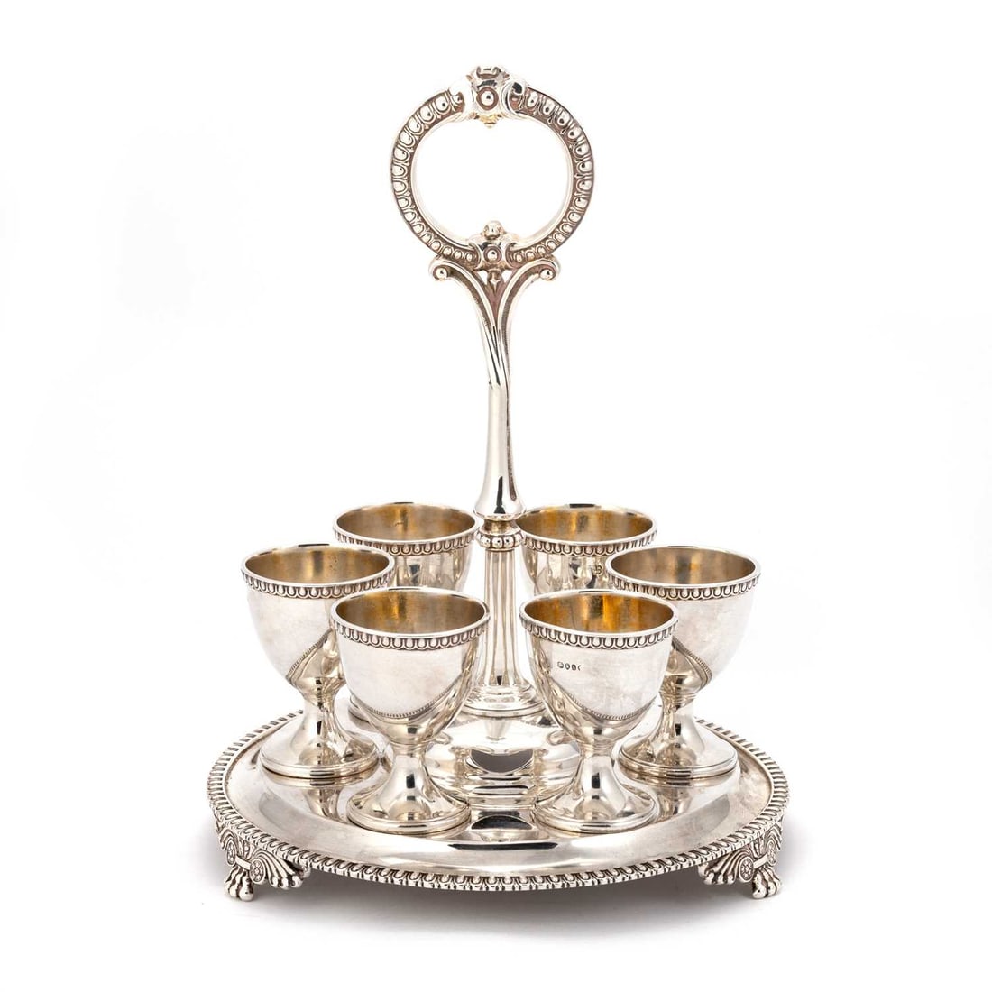A VICTORIAN SILVER EGG CRUET: A VICTORIAN SILVER EGG CRUET by Edward & John Barnard, London 1865, the circular stand with a beaded handle, supporting six egg cups, all with matching marks, the base with an egg moulded border a