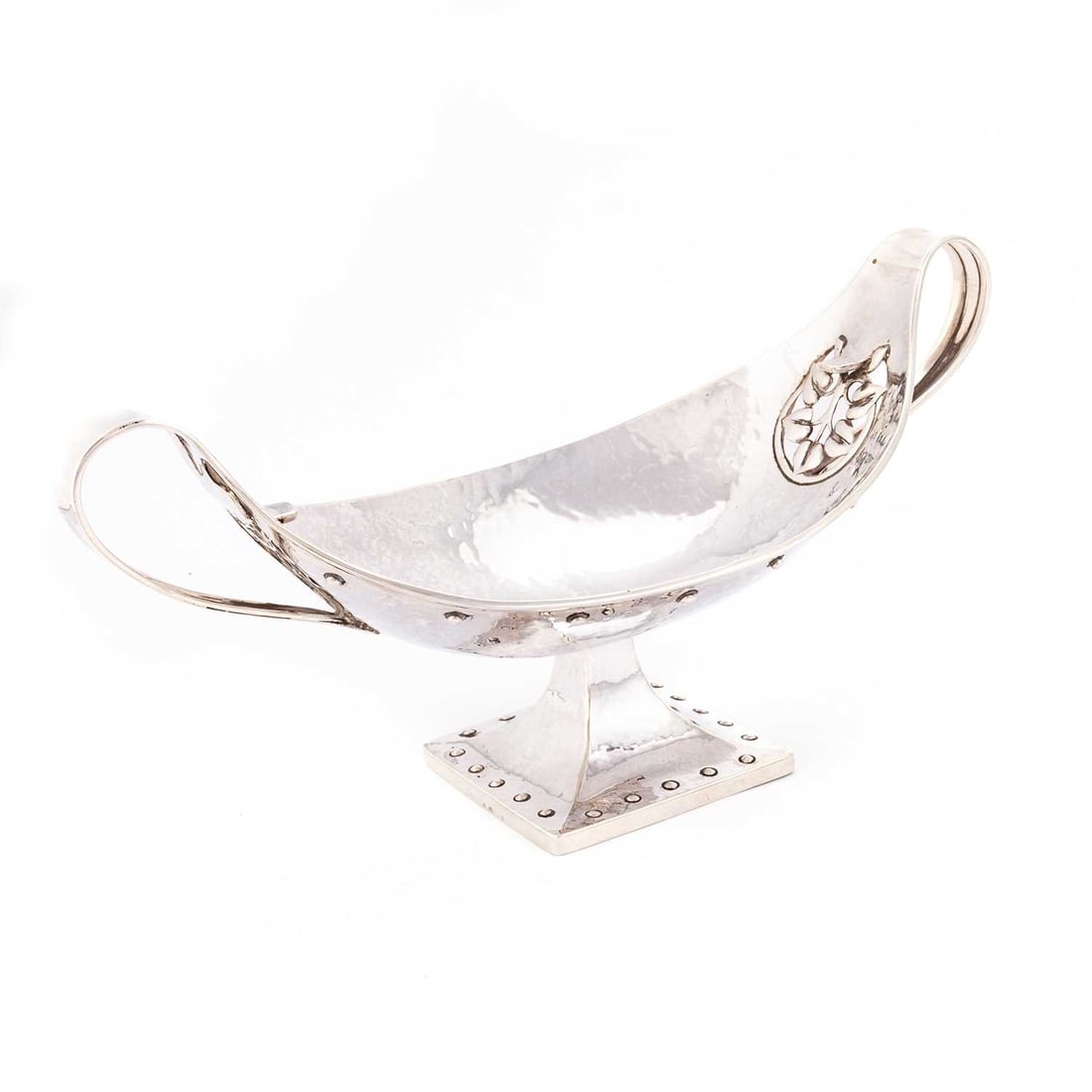 A.E. JONES: AN ARTS AND CRAFTS SILVER TWO-HANDLED BOWL: A.E. JONES: AN ARTS AND CRAFTS SILVER TWO-HANDLED BOWL by Albert Edward Jones, Birmingham 1917, oval, the spot-hammered bowl with a pierced and chased foliate roundel to either end, to the exterior be