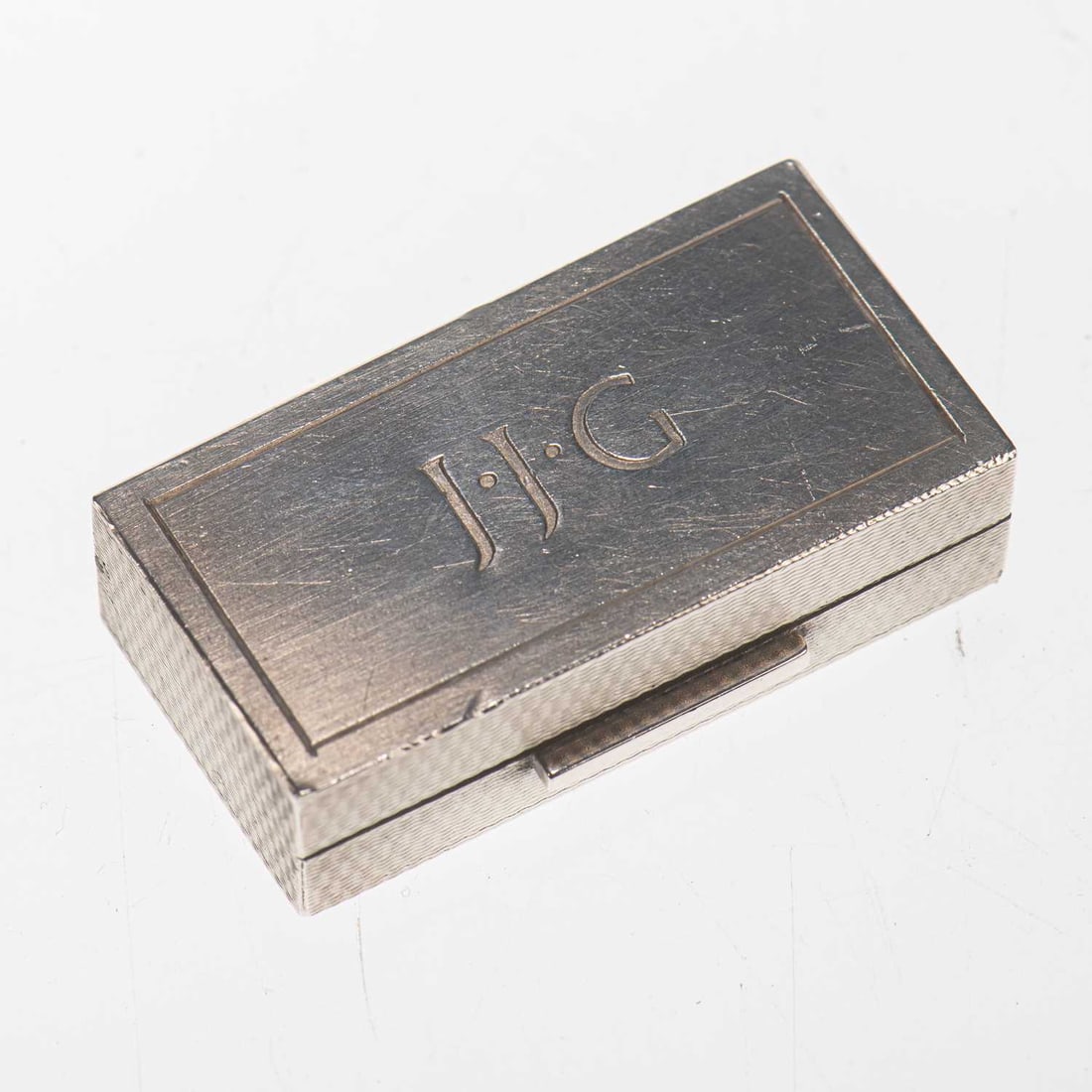 AN ELIZABETH II SILVER PILL BOX: AN ELIZABETH II SILVER PILL BOX by Asprey & Co Ltd, Birmingham 1990, rectangular, engine-turned and engraved with the initials. 5cm wide, 1.8 troy ounces The marks are clear. The box is in very g