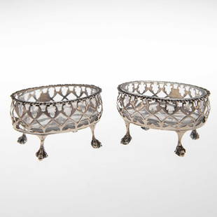 A PAIR OF GEORGE III SILVER SALTS: A PAIR OF GEORGE III SILVER SALTS by Hester Bateman, London 1787, both of oval form, with pierced sides and gadrooned rims, each raised on four ball and claw feet, glass liners. (2) 8.2cm wide, 3.5 tr