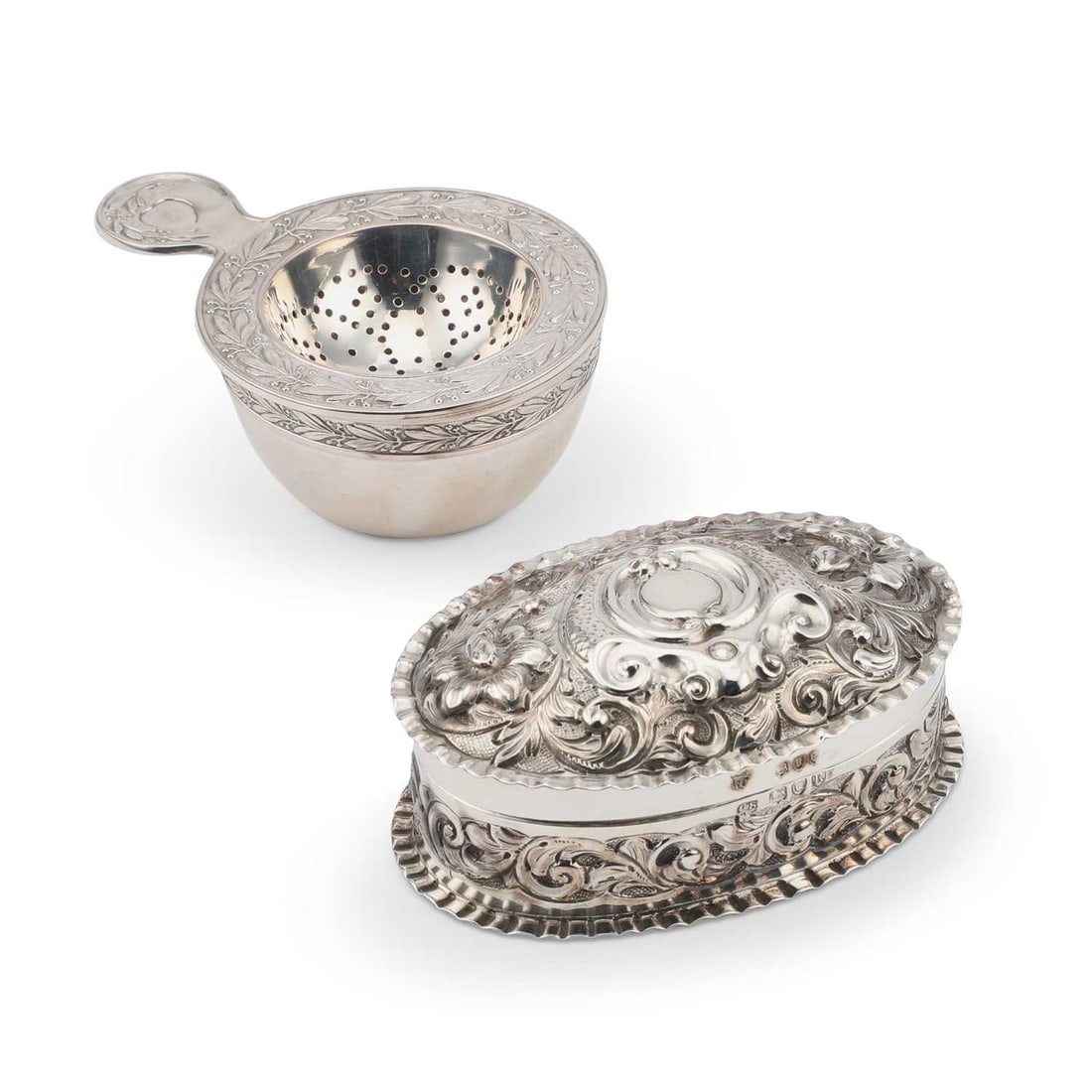 A VICTORIAN SILVER BOX: A VICTORIAN SILVER BOX by Charles Stuart Harris, London 1892, oval form with a pull-off cover, boldly embossed with flowers and scrolls; together with a Continental 800 grade silver tea strainer, the