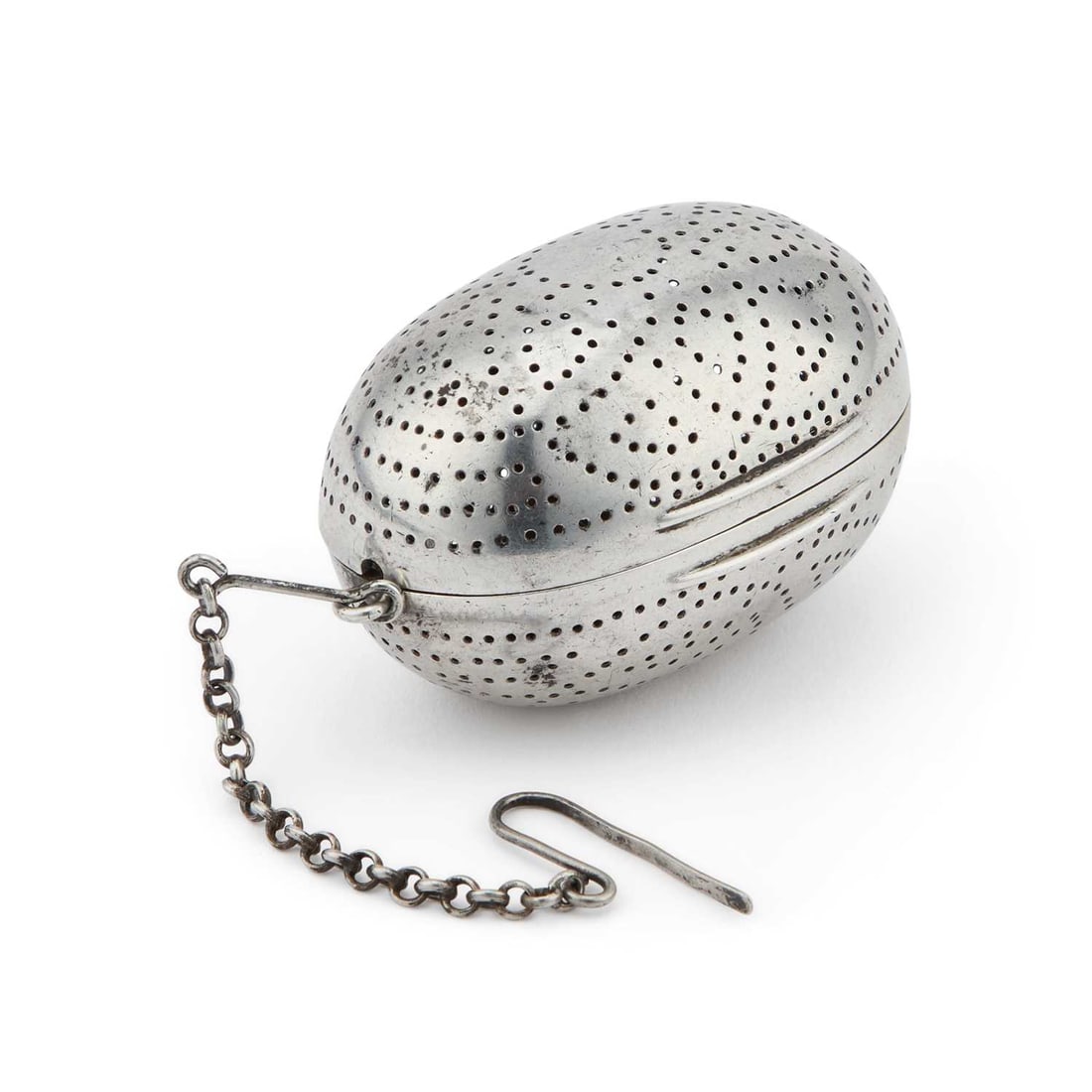 A VICTORIAN SILVER TEA INFUSER: A VICTORIAN SILVER TEA INFUSER by Thomas Johnson I, London 1865, of ovoid form, pierced to each side, the hinged cover opening to reveal a gilded interior, suspended from a hook and chain. 6cm wide,