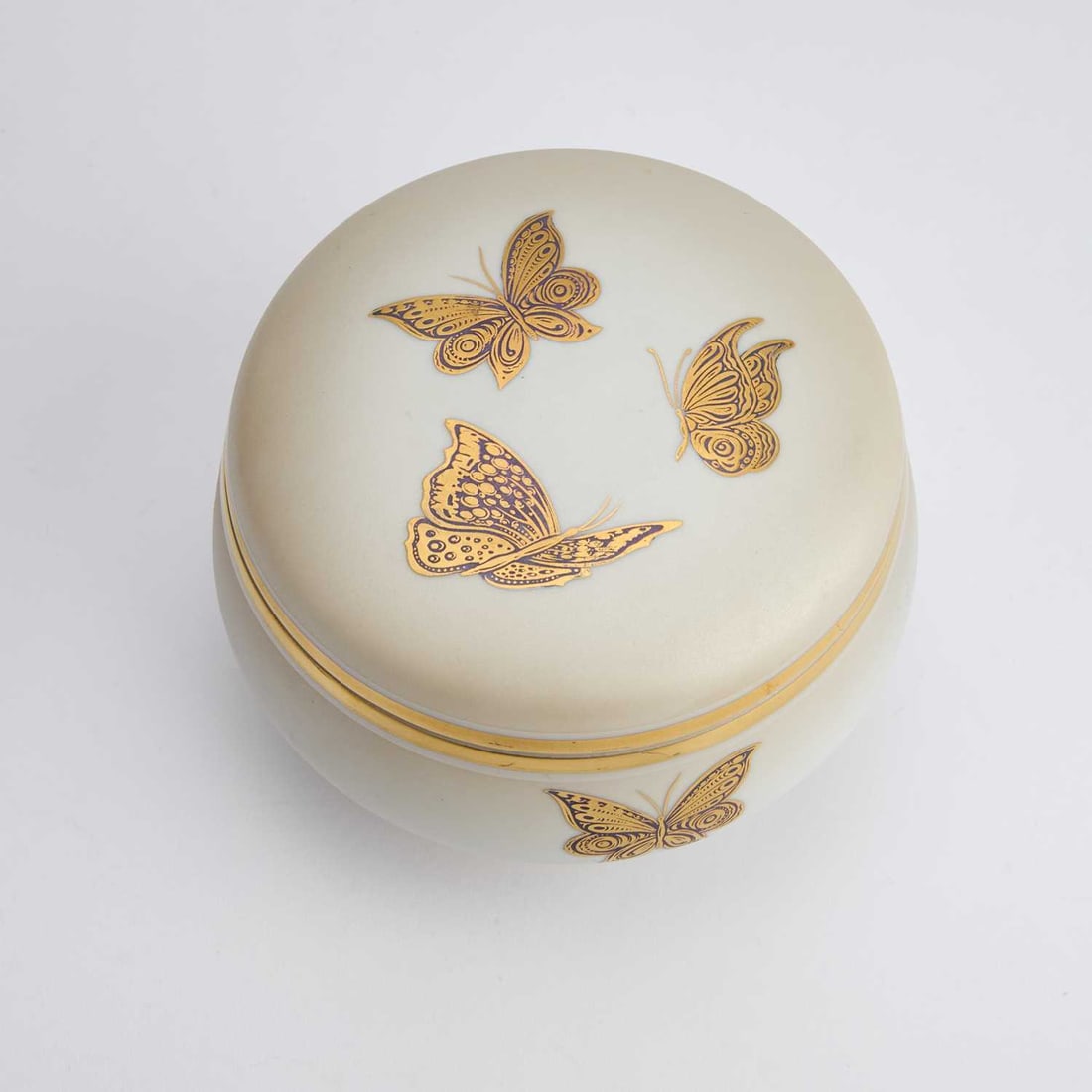 A MID-CENTURY ITALIAN PORCELAIN JEWELLERY BOX BY LONGO, LATE 1960S: A MID-CENTURY ITALIAN PORCELAIN JEWELLERY BOX BY LONGO, LATE 1960S circular, decorated with butterflies, printed and gilded mark. 9cm high, 13cm diameter