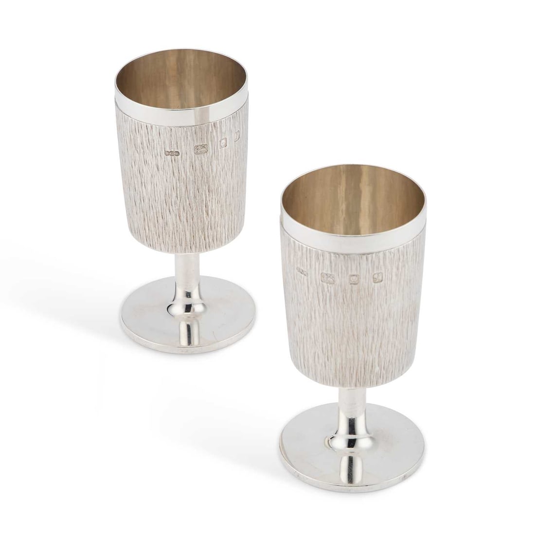 GERALD BENNEY: A PAIR OF ELIZABETH II SILVER GOBLETS: GERALD BENNEY: A PAIR OF ELIZABETH II SILVER GOBLETS by Gerald Benney, London 1966, the slightly curved bark effect textured surface below a polished rim, raised on a polished stem and circular foot,