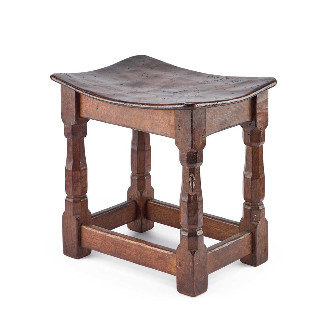 ROBERT THOMPSON OF KILBURN, A MOUSEMAN BURR OAK DISH TOP STOOL: ROBERT THOMPSON OF KILBURN, A MOUSEMAN BURR OAK DISH TOP STOOL with nailed and adzed top on four octagonal legs joined by stretchers, with carved mouse signature. 37cm high, 38cm wide, 28cm deep It i